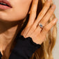 Woman wearing the BATHILDA rustic ring, a silver-plated, hammered-texture piece on her middle finger, showcasing bold elegance against a black ruffled-edge sleeve.