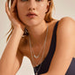 Woman wearing CAROL layered necklace 3-in-1 silver-plated, featuring small coins and crystals, styled for a bohemian look. Perfect for layering with outfits.