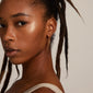 Woman with dreadlocks wearing MAJA crystal waterfall hoop earrings, featuring asymmetrical gold pendants with Preciosa crystals, adding a stylish edge.