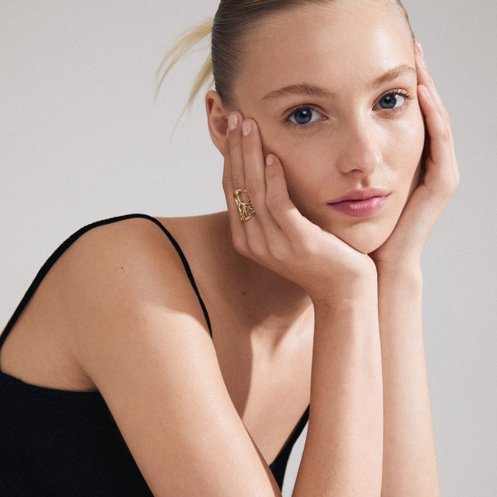 Close-up of a woman showcasing the ALIA ring, gold-plated, featuring the Tree of Life design. The ring elegantly complements her personal style.