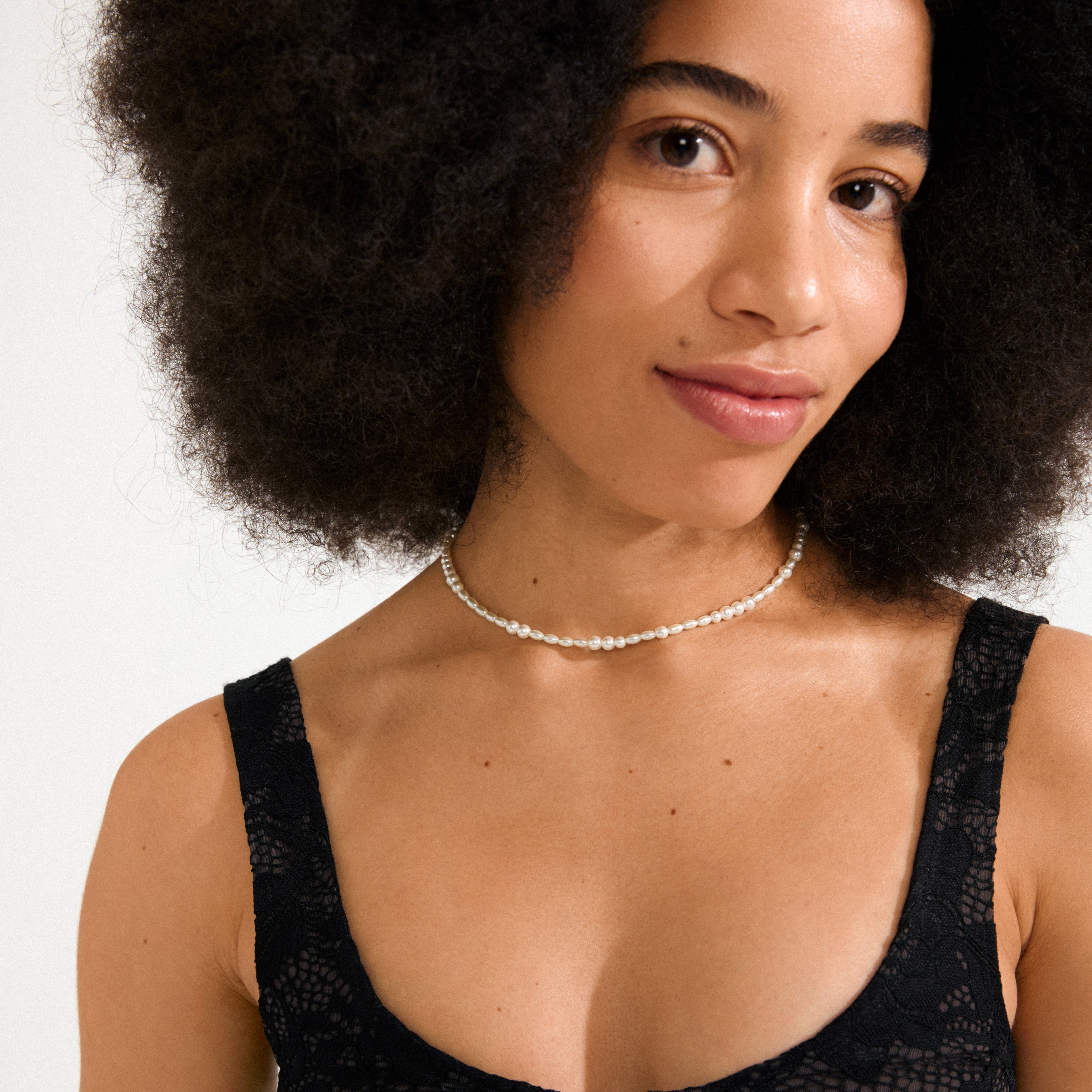 ELLIANA necklace gold-plated on a woman, featuring genuine freshwater pearls and mother-of-pearl glass beads, offering a modern twist to classic elegance.