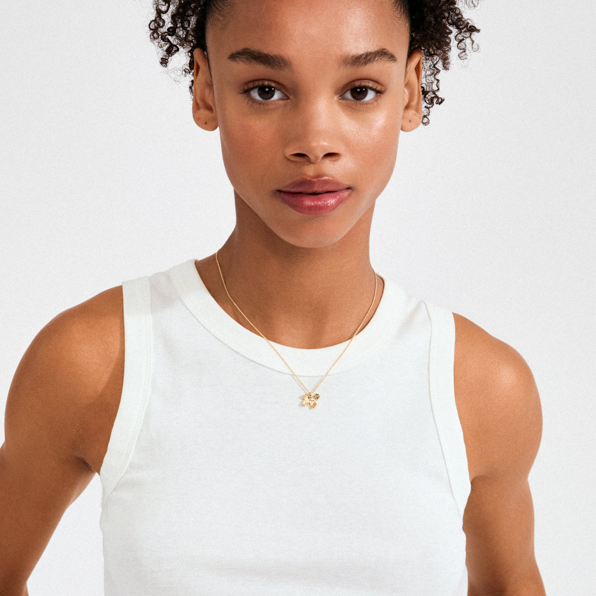 AJANI necklace gold-plated, featuring a delicate floral pendant, worn by a woman in a white tank top, embodying Pilgrim's handcrafted, timeless style.
