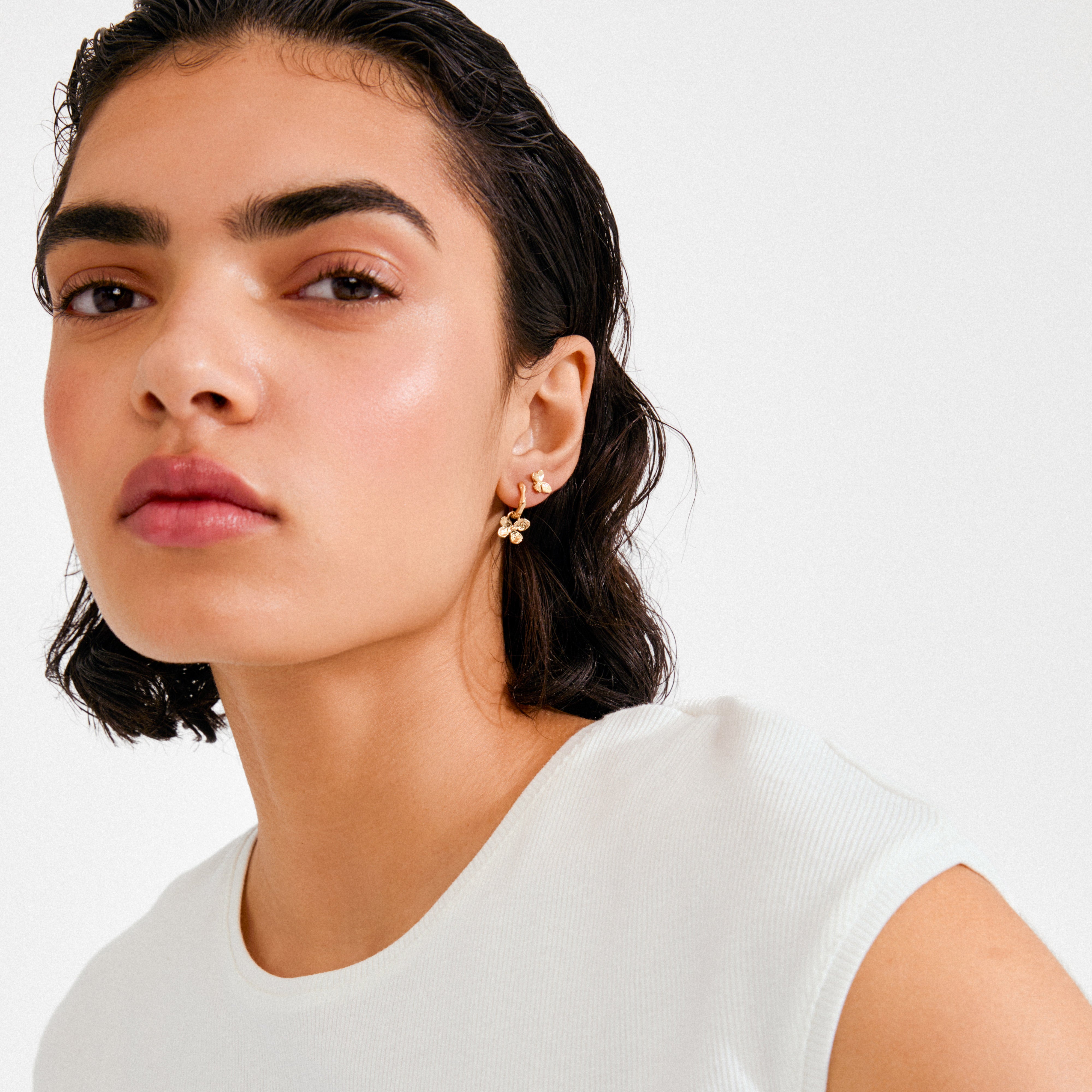 AJANI earrings 2-in-1 set, gold-plated, shown worn by a woman, highlighting the dainty hoop with a flower charm, embodying Pilgrim's elegant and versatile design.