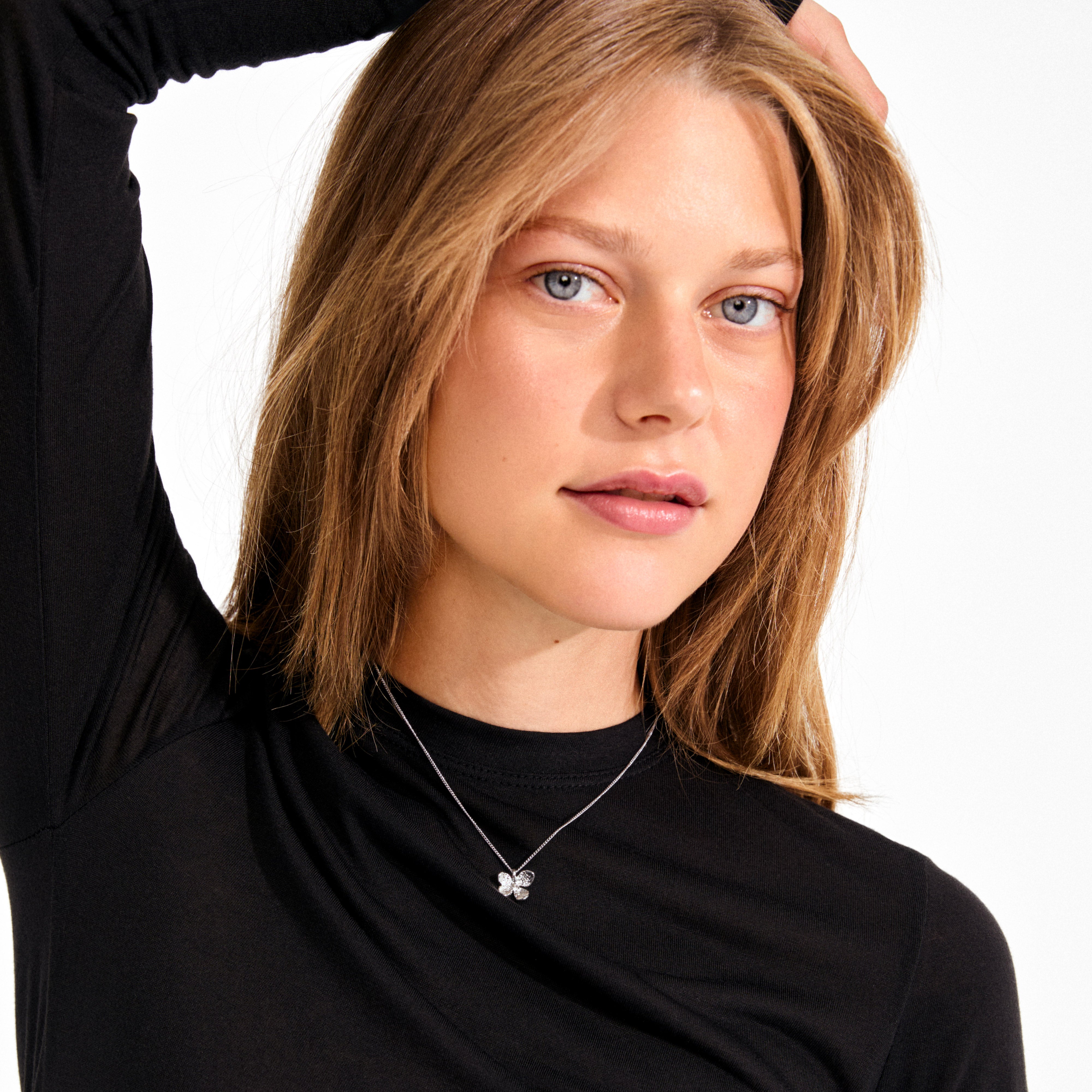 AJANI necklace silver-plated: Delicate clover-shaped pendant on a silver chain, worn by a young woman, embodying Pilgrim's artisan, nature-inspired elegance.