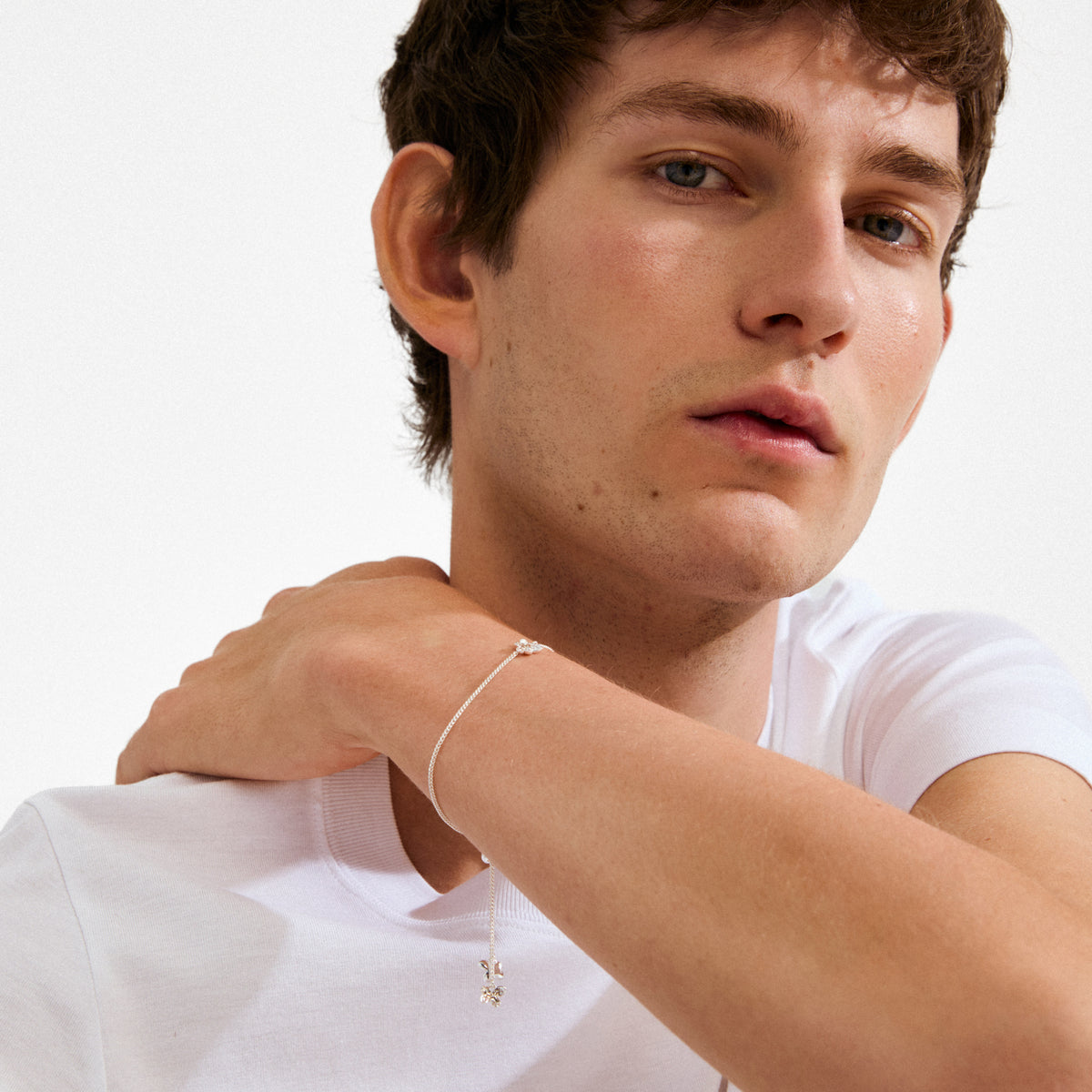 Young man wearing the AJANI bracelet, a silver-plated piece with a dainty floral charm, showcasing Pilgrim's minimalist, Scandinavian-inspired jewelry design.