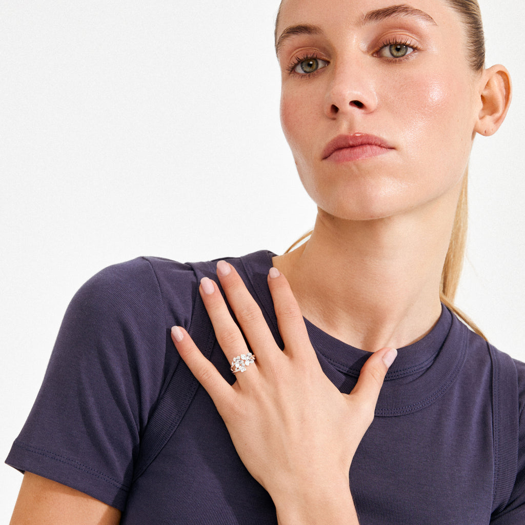 Woman wearing a simple T-shirt showcases the AJANI ring, a silver-plated, nature-inspired piece with multi-stone cluster, highlighting Pilgrim's handcrafted, Scandinavian style.