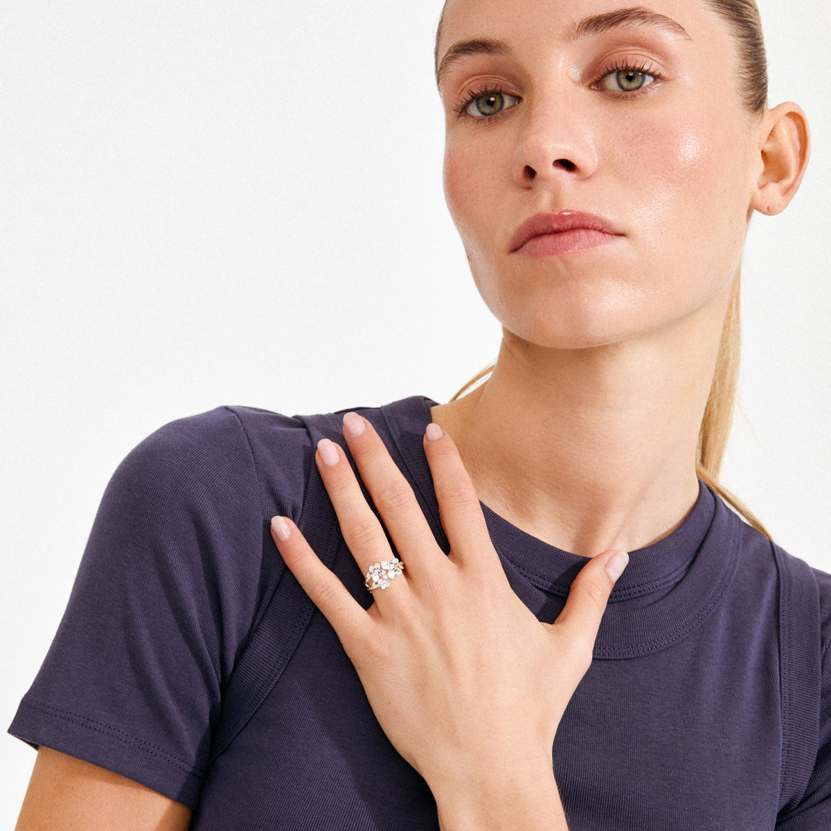 Woman wearing a simple T-shirt showcases the AJANI ring, a silver-plated, nature-inspired piece with multi-stone cluster, highlighting Pilgrim's handcrafted, Scandinavian style.