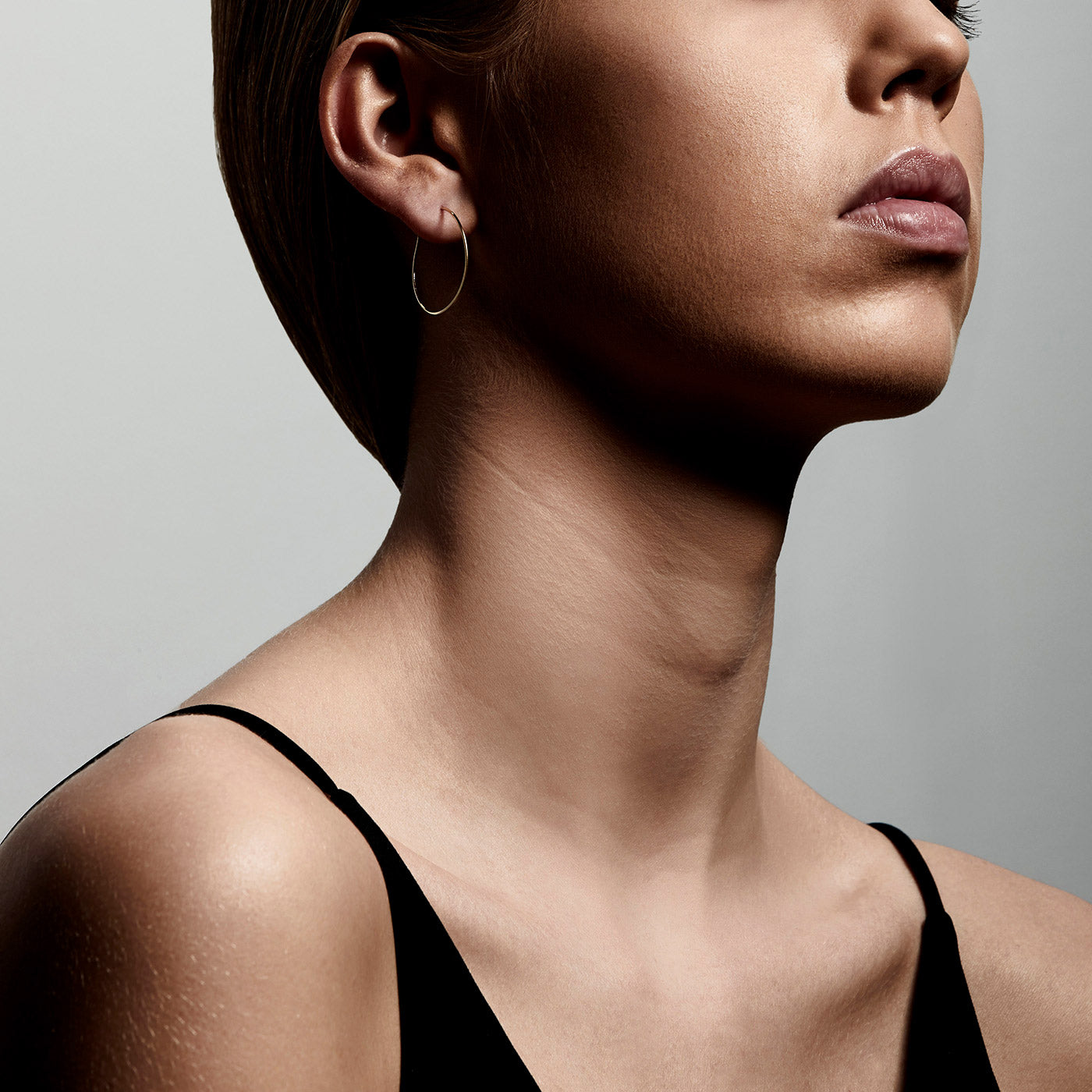 Gold-plated TILLY earrings featured on a woman in a black dress, showcasing their elegance and versatility for both everyday and evening wear.