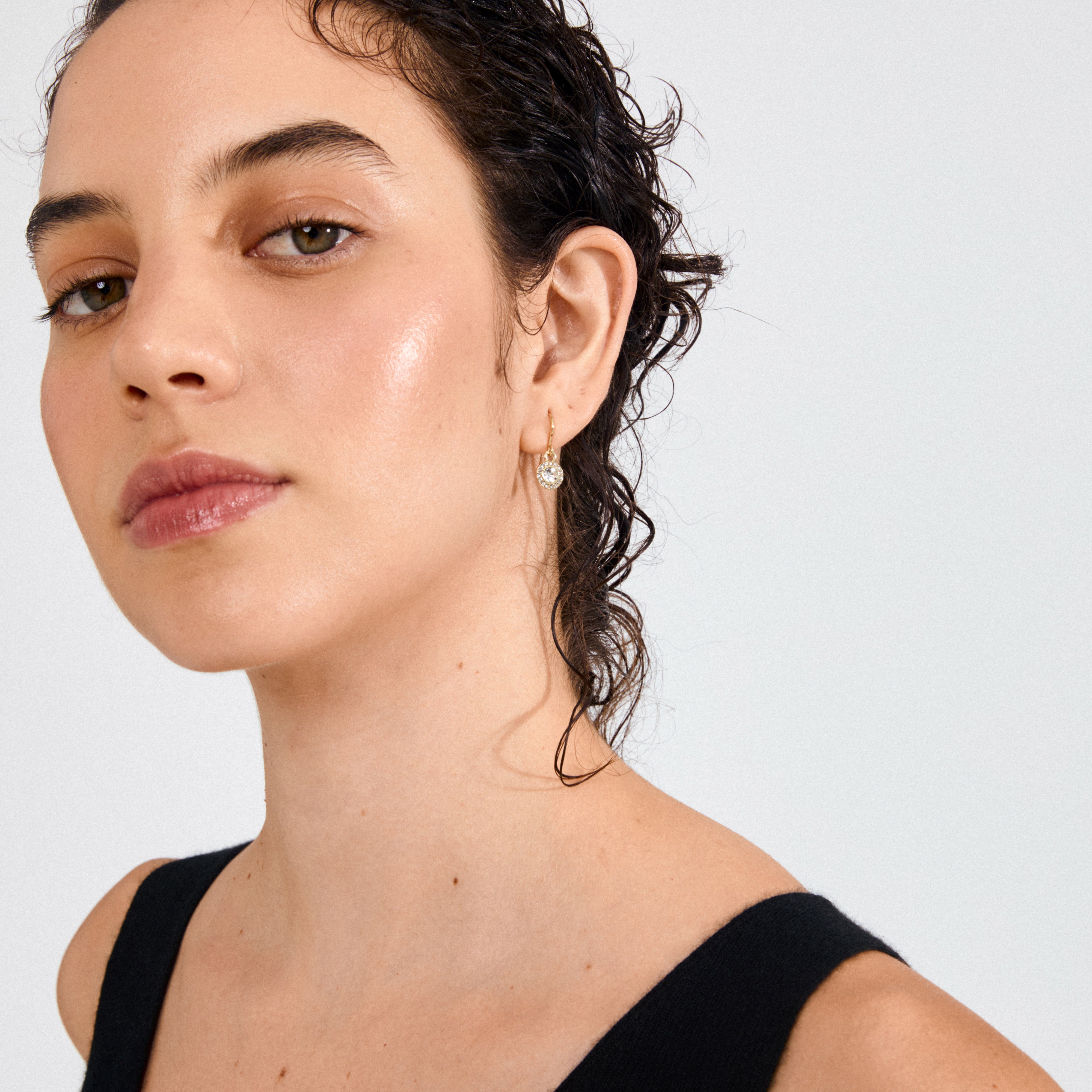 Young woman wearing CLEMENTINE crystal earrings gold-plated, featuring sparkling Preciosa crystals and tiny stones, adding an ethereal touch to her elegant look.