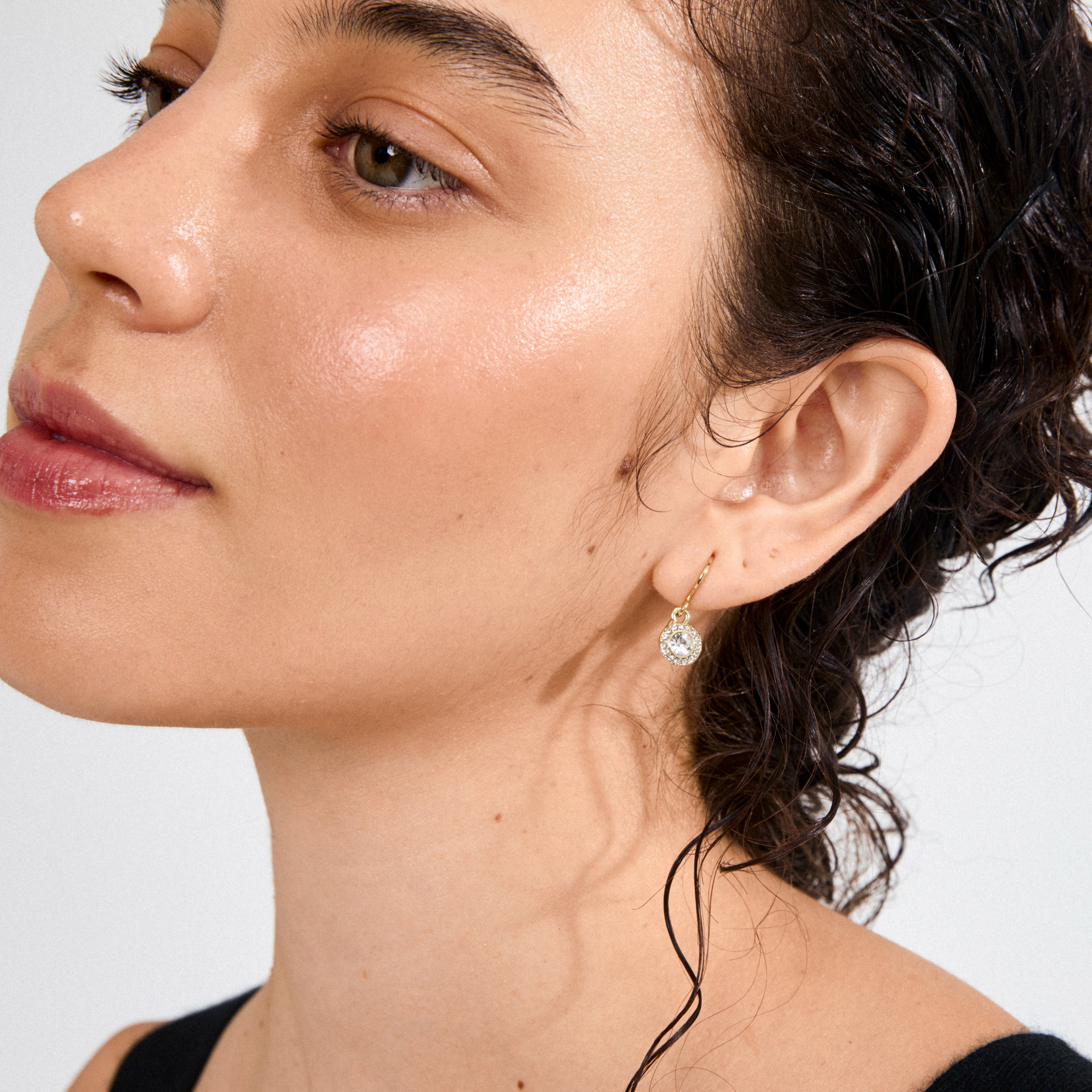 CLEMENTINE crystal earrings gold-plated, featuring a shimmering Preciosa crystal pendant, adorn a woman's ear, embodying elegance and an ethereal glow.