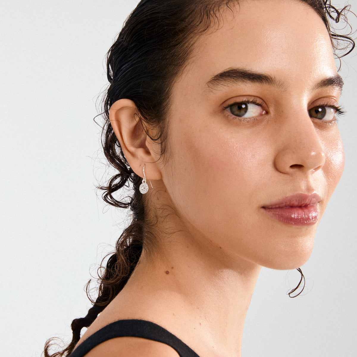 Young woman wearing CLEMENTINE crystal earrings silver-plated, featuring a central Preciosa crystal and surrounding sparkling stones, showcasing elegant, eco-conscious Danish design by Pilgrim.