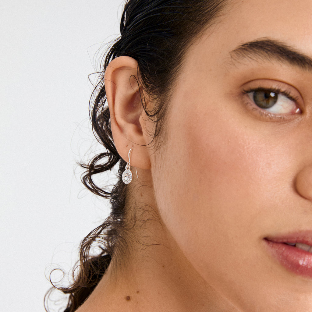 CLEMENTINE crystal earrings silver-plated, featuring a central Preciosa crystal surrounded by sparkling stones, elegantly displayed on a person with dark hair and minimal makeup.