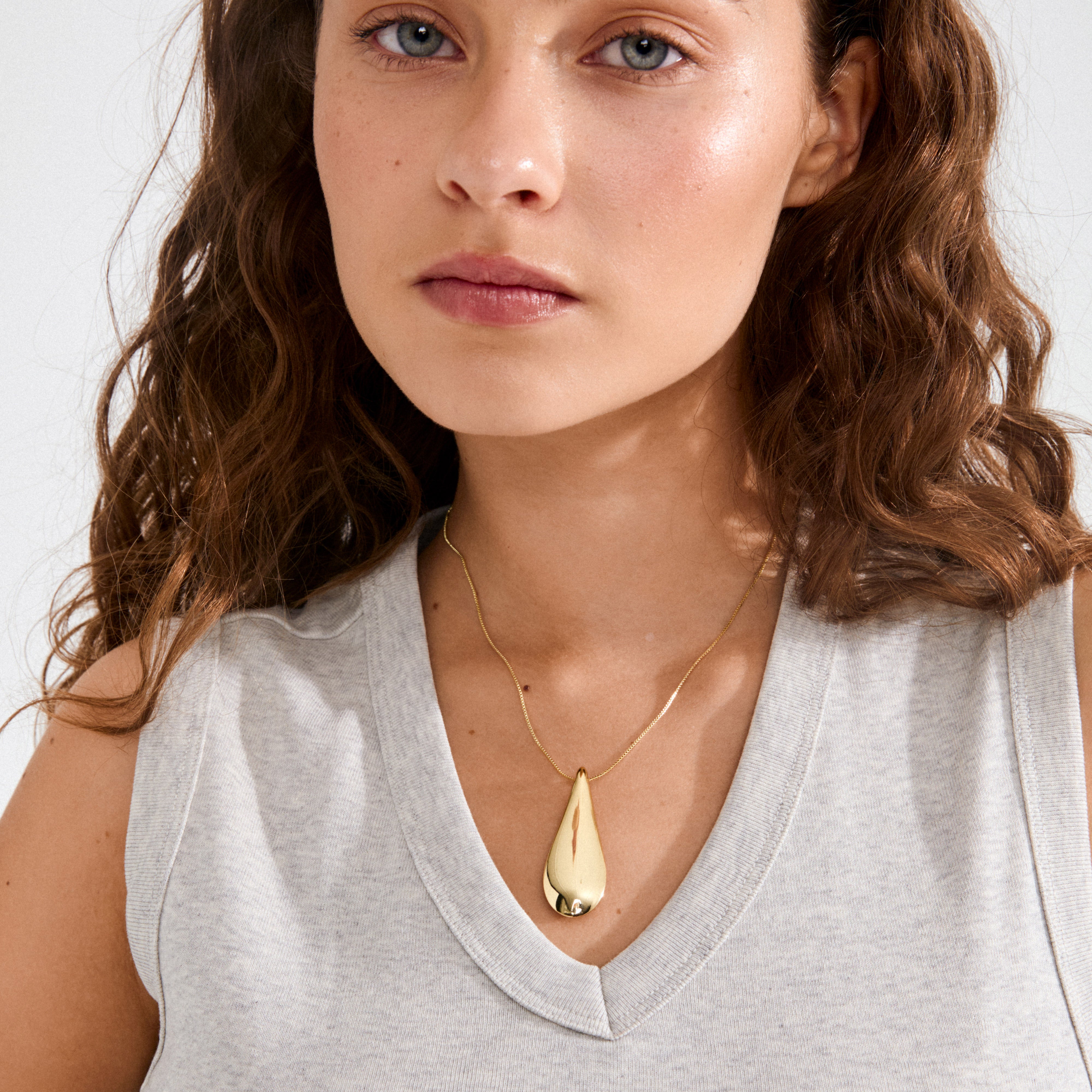 Close-up of a woman wearing the ALMA gold-plated necklace, featuring a teardrop pendant on a fine chain, embodying Nordic-inspired minimalism and crafted from recycled materials.