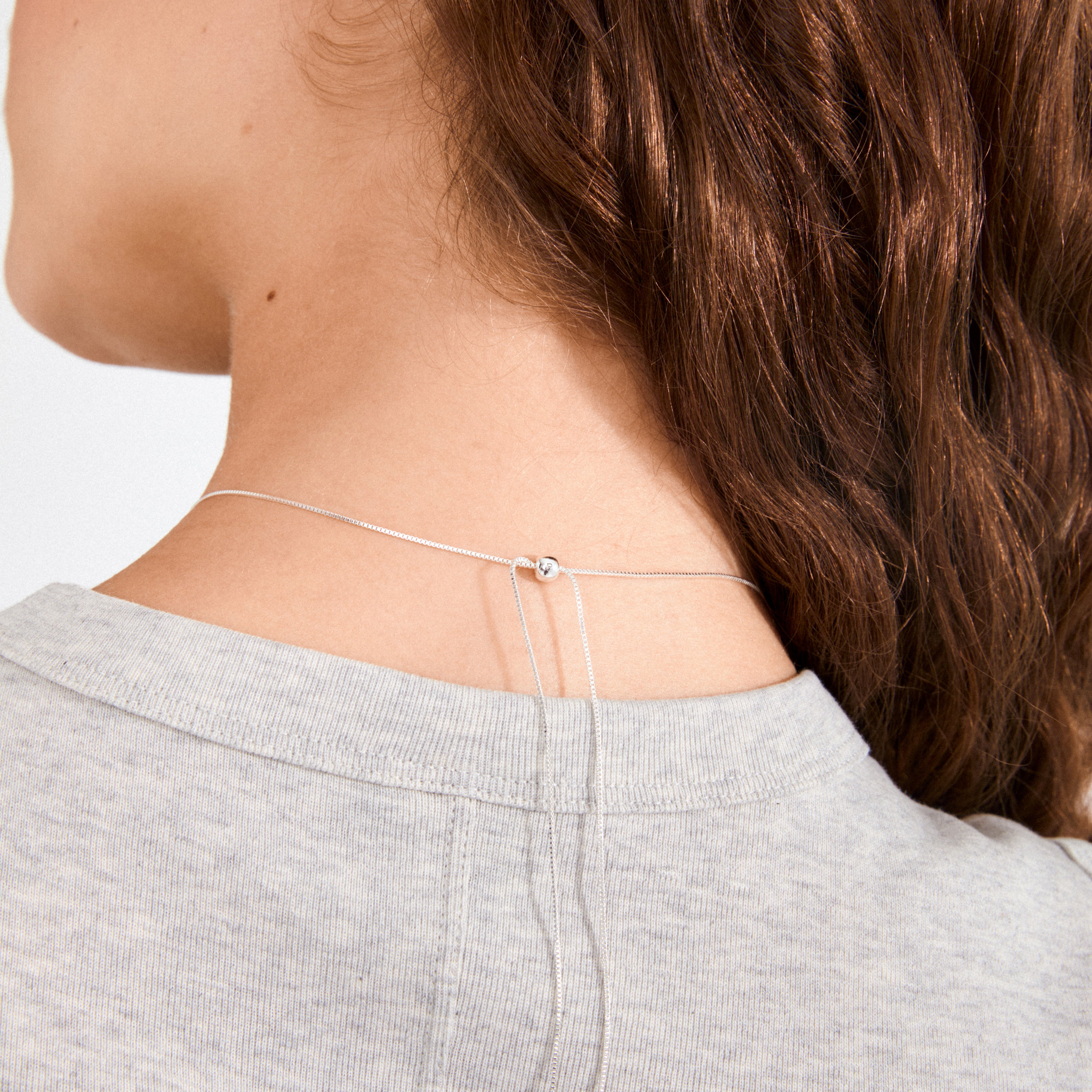 ALMA necklace silver-plated shown with an adjustable silver slider on the neck, highlighting its Nordic-inspired minimalism and versatility with recycled materials.