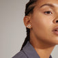 QUINN organic shaped crystal earrings, silver-plated, small ear studs with unique design and Preciosa crystals, worn by woman with braided hair.