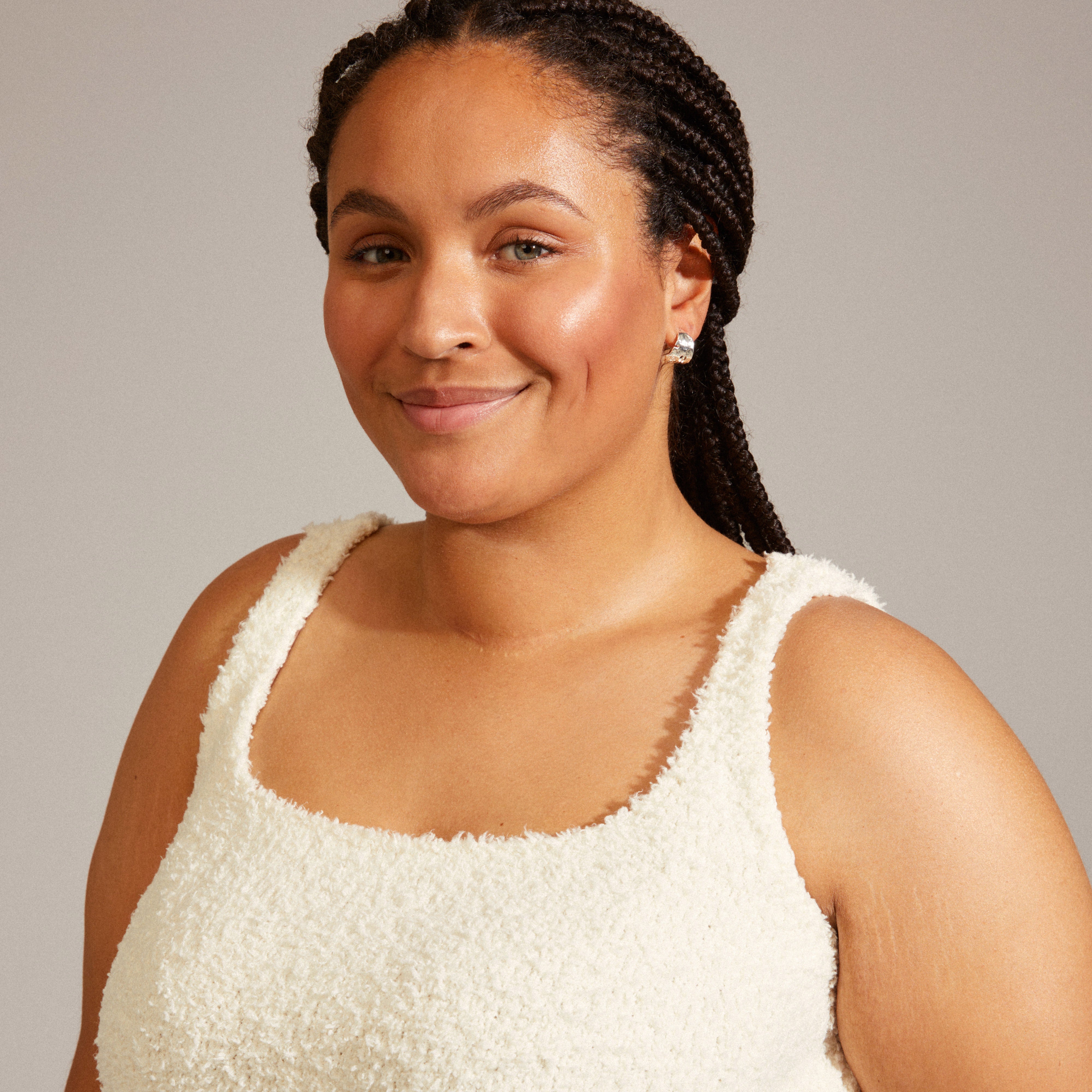 BRENDA earrings silver-plated showcased by a smiling woman, featuring wide semi hoops with irregular surfaces, reflecting a handcrafted, nature-inspired design.