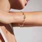 Woman wearing the gold-plated PRUCENCE bracelet by Pilgrim, adorned with charms and a freshwater pearl, symbolizing love and dreams.
