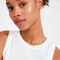 Close-up of a person's neck wearing Pilgrim's NIKITA necklace, a gold-plated, wavy choker-style chain, elegantly draped over a white sleeveless top.