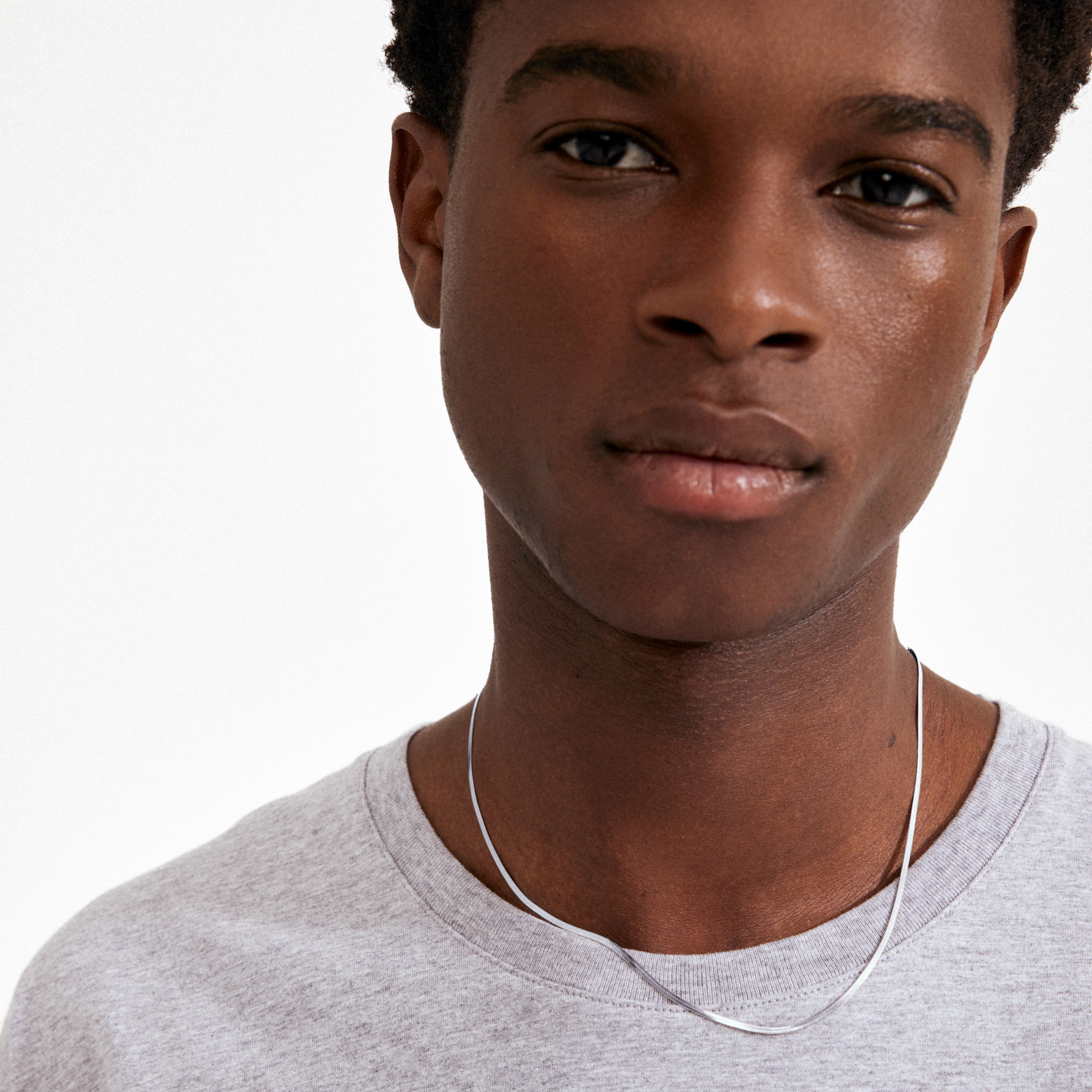 Close-up of a young person wearing Pilgrim's NIKITA silver-plated herringbone chain, showcasing its smooth, elegant drape and chic, genderless style.