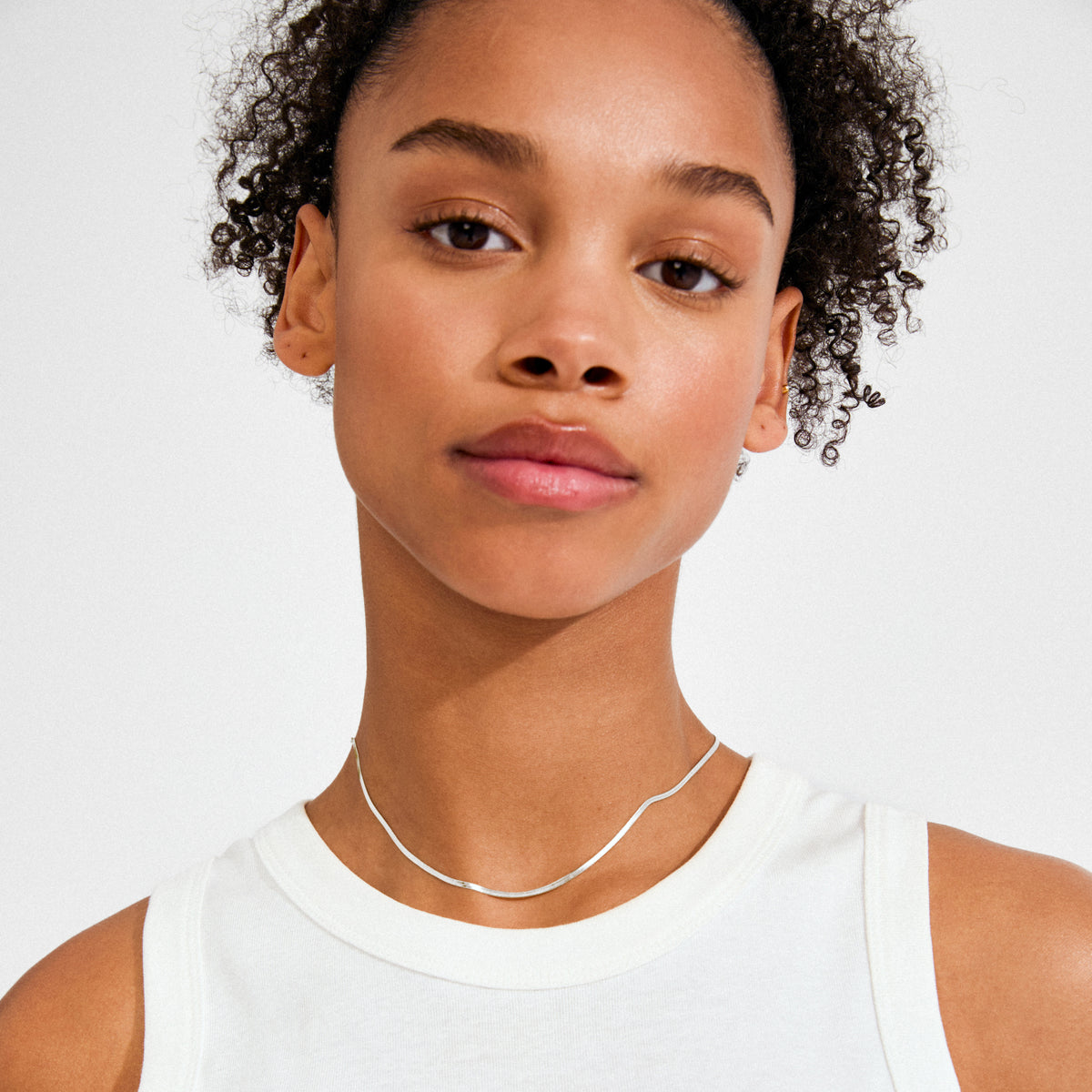 Young woman in a white top wearing the Pilgrim NIKITA necklace, a sleek, silver-plated herringbone chain that exudes effortless style and elegance.