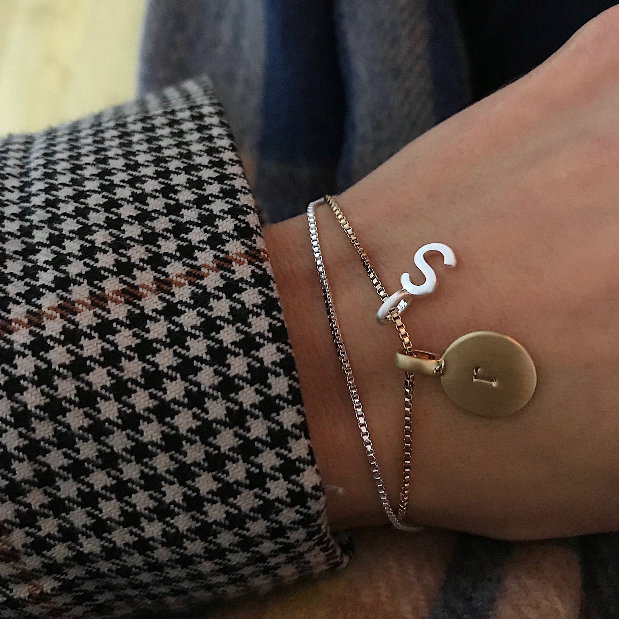 VERA gold-plated bracelet with an initial charm, worn on a wrist, ideal for stacking or customizing with additional charms.