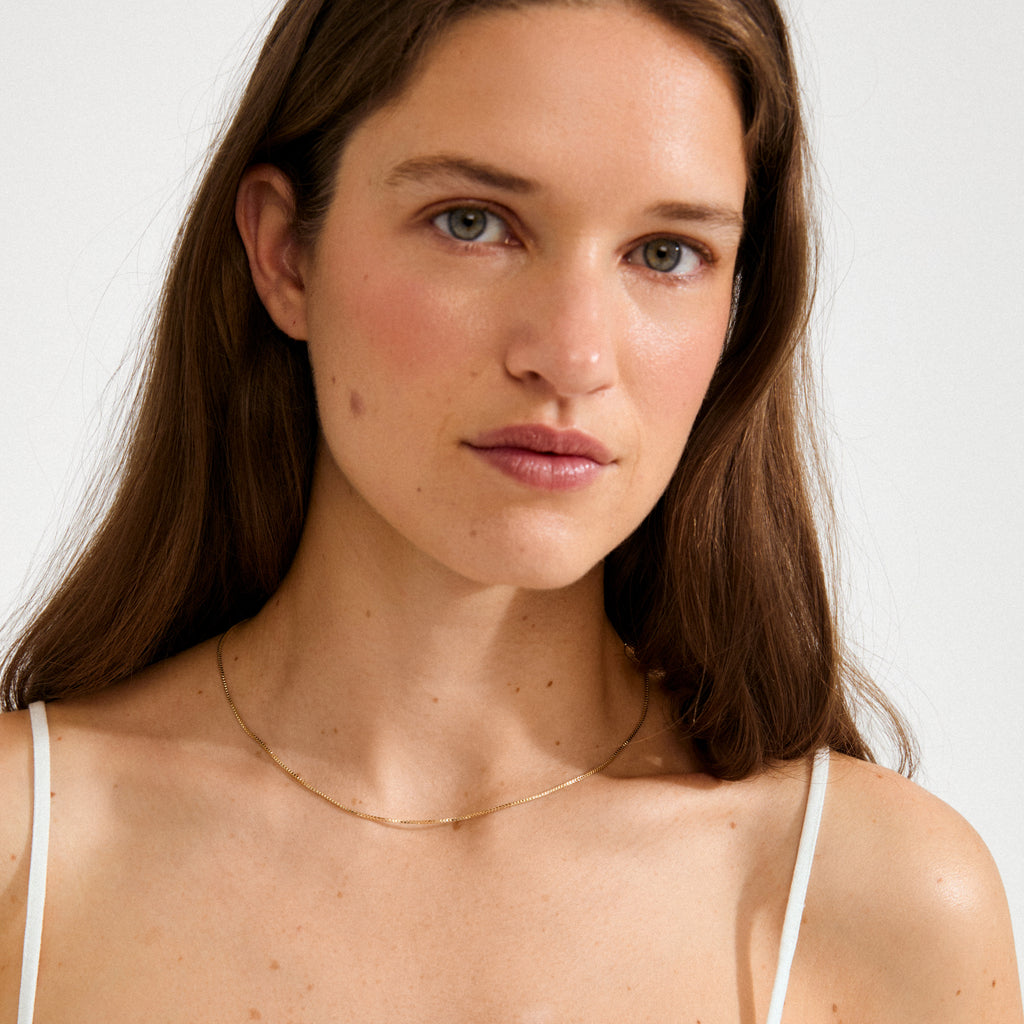 Young woman wearing the NANCY necklace, a 45 cm gold-plated Venezia chain, showcasing its simplicity and elegance for versatile, stylish layering.