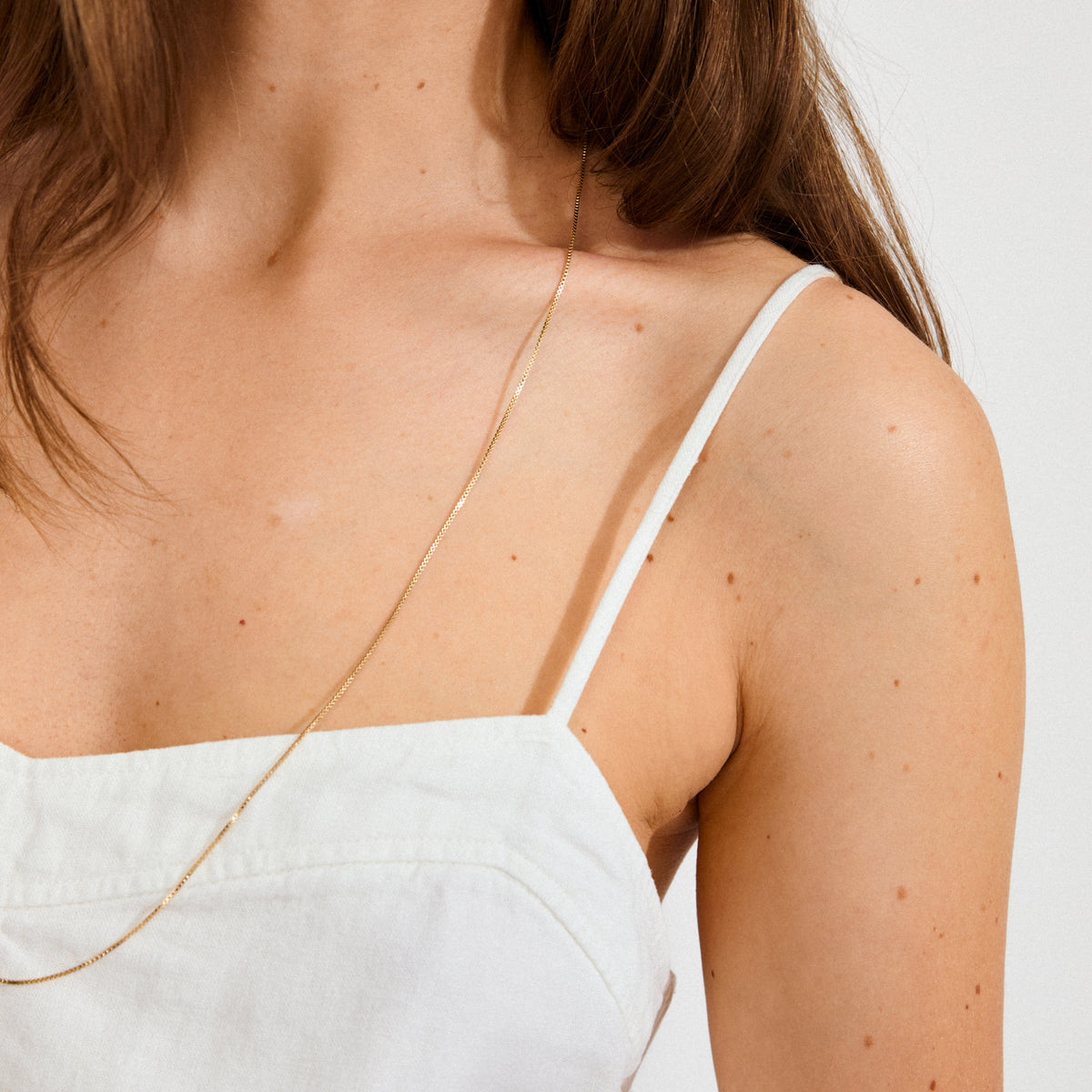 Person wearing the NANCY necklace, 80 cm gold-plated, showcasing its elegance and simplicity against a light background, perfect for layering with other Pilgrim pieces.