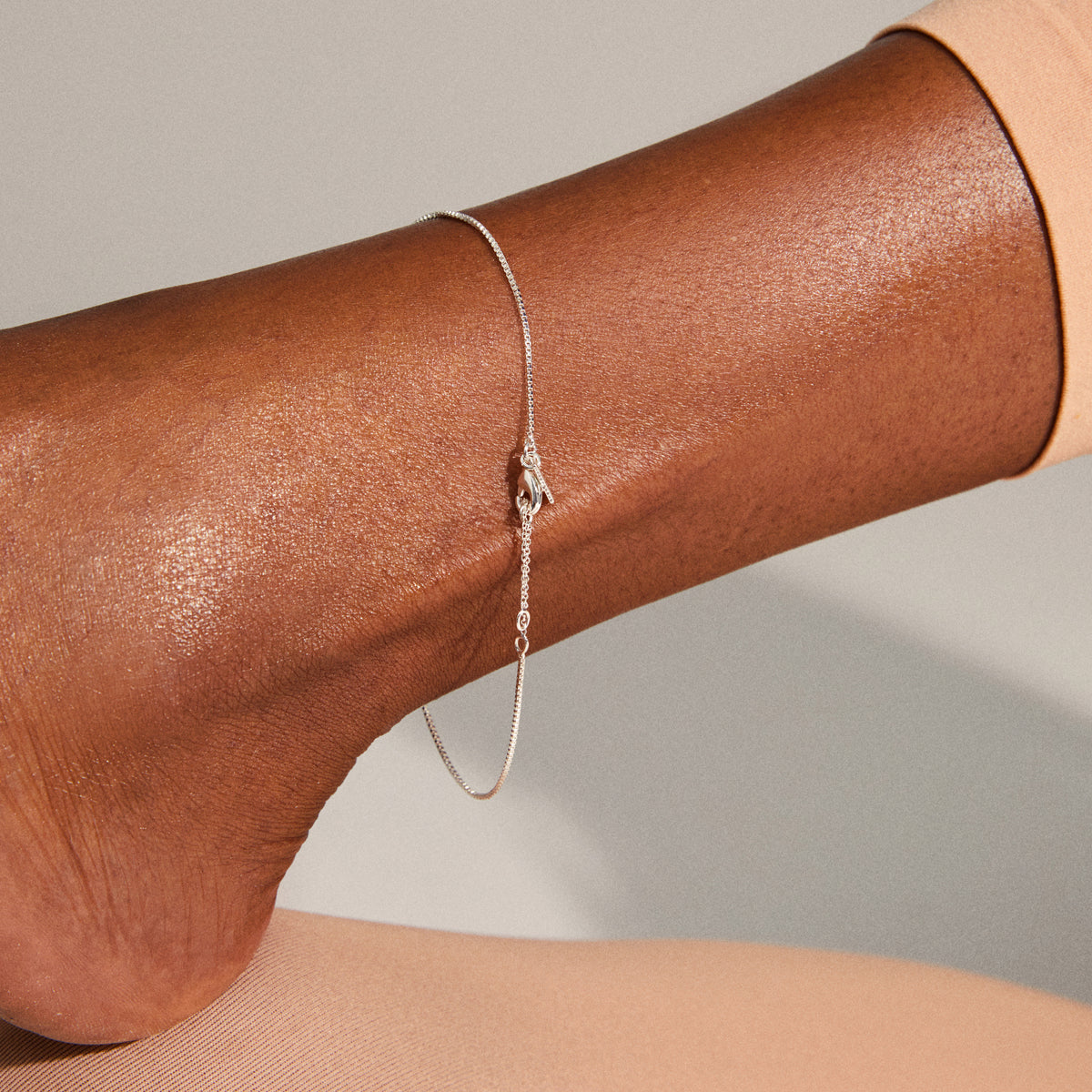PALLAS anklet silver-plated elegantly draped on a person's ankle, showcasing its delicate chain detail. Perfect for enhancing personal style with a trendy, feminine touch.