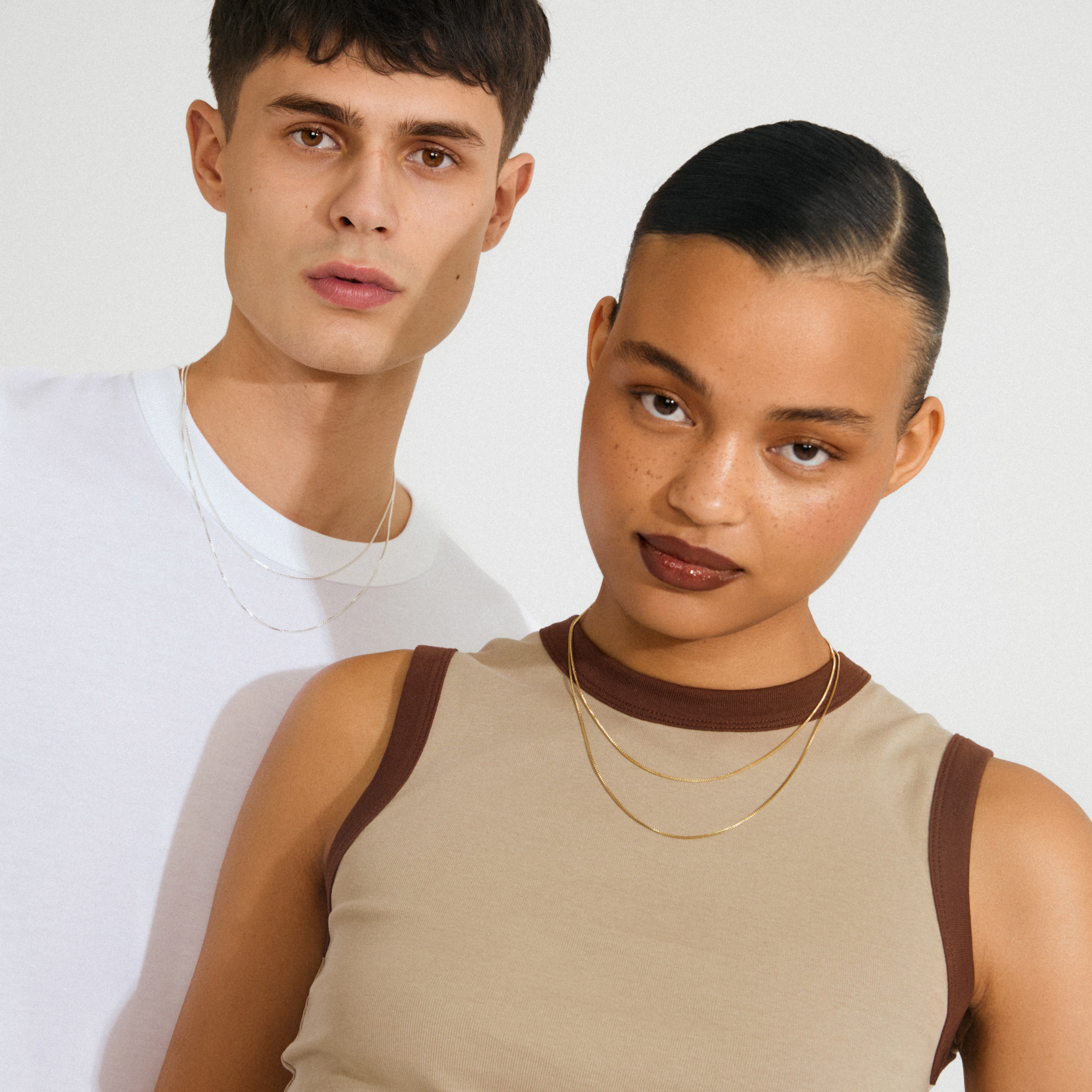 Young woman wearing the NANCY necklace 45 cm silver-plated, paired with another gold necklace, showcasing a sleek, layered look against a minimalist backdrop.