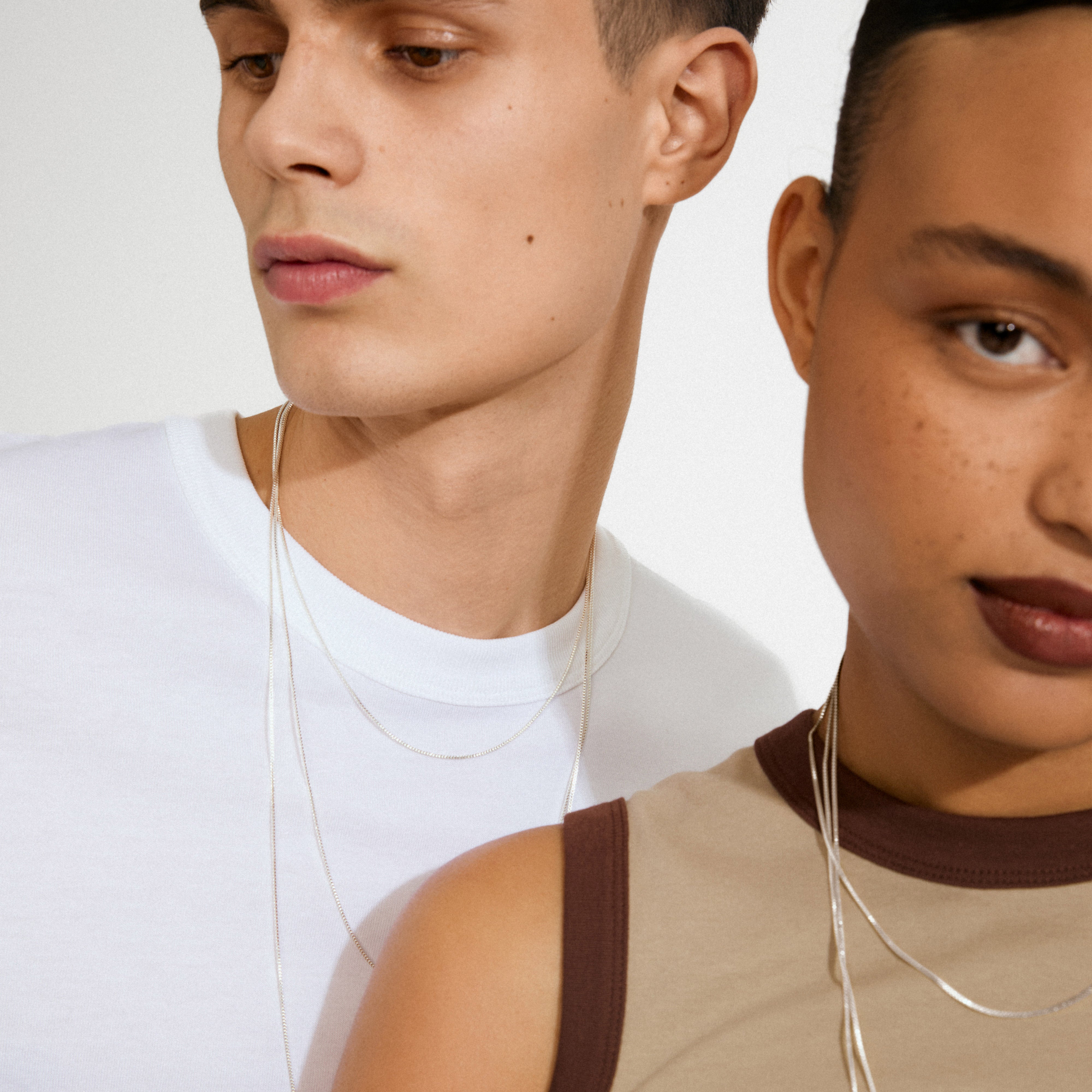 Models wear minimalist silver chain necklaces, showcasing the NANCY necklace, an 80 cm silver-plated piece ideal for layering with charms and pendants.
