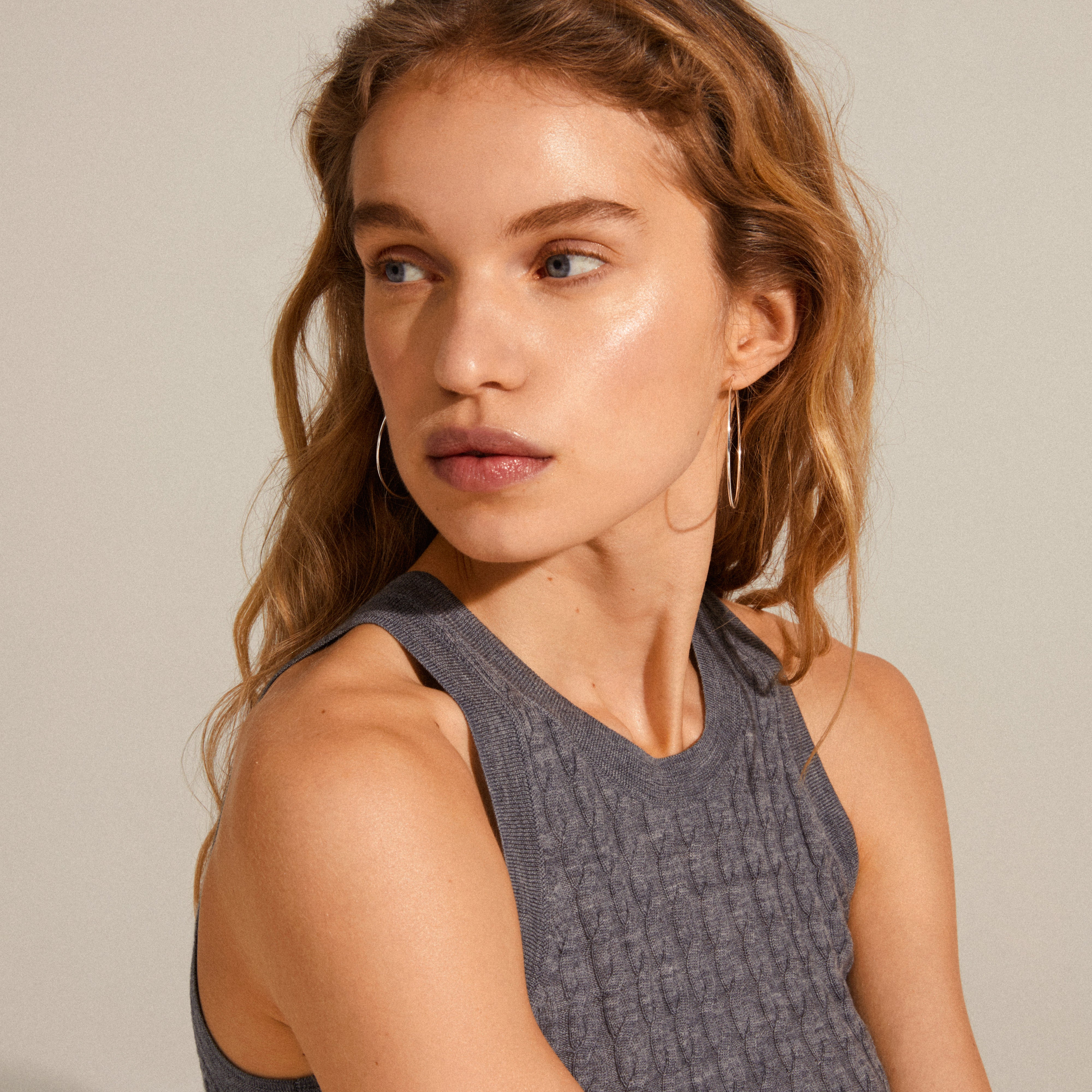 SANNE large hoop earrings, silver-plated, worn by a woman looking sideways. The 45 mm hoops exemplify timeless elegance, ideal for everyday wear and versatile styling.