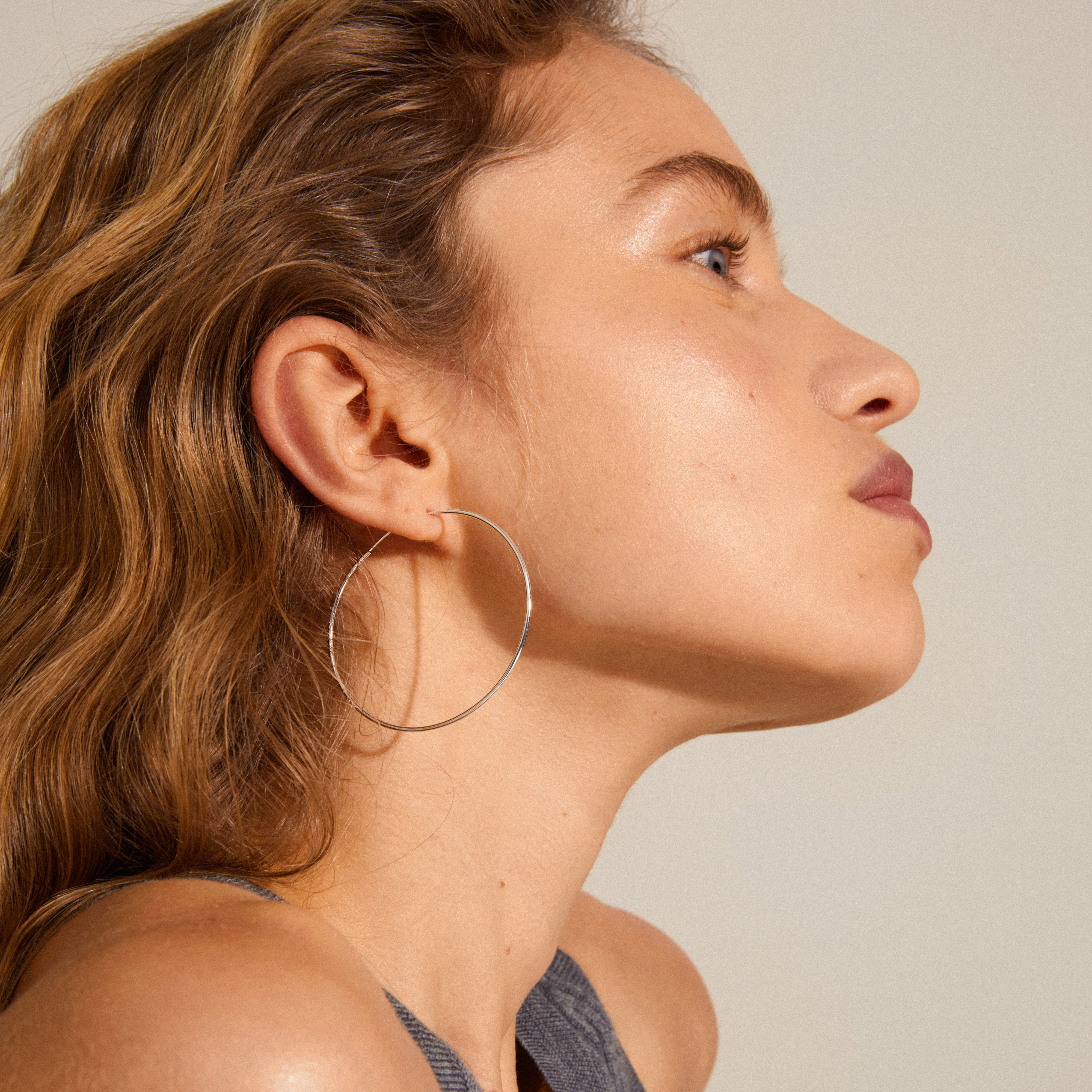 SANNE large hoop earrings in silver-plated finish, worn by a woman, showcasing the classic 45 mm design for timeless elegance. Ideal for versatile styling.
