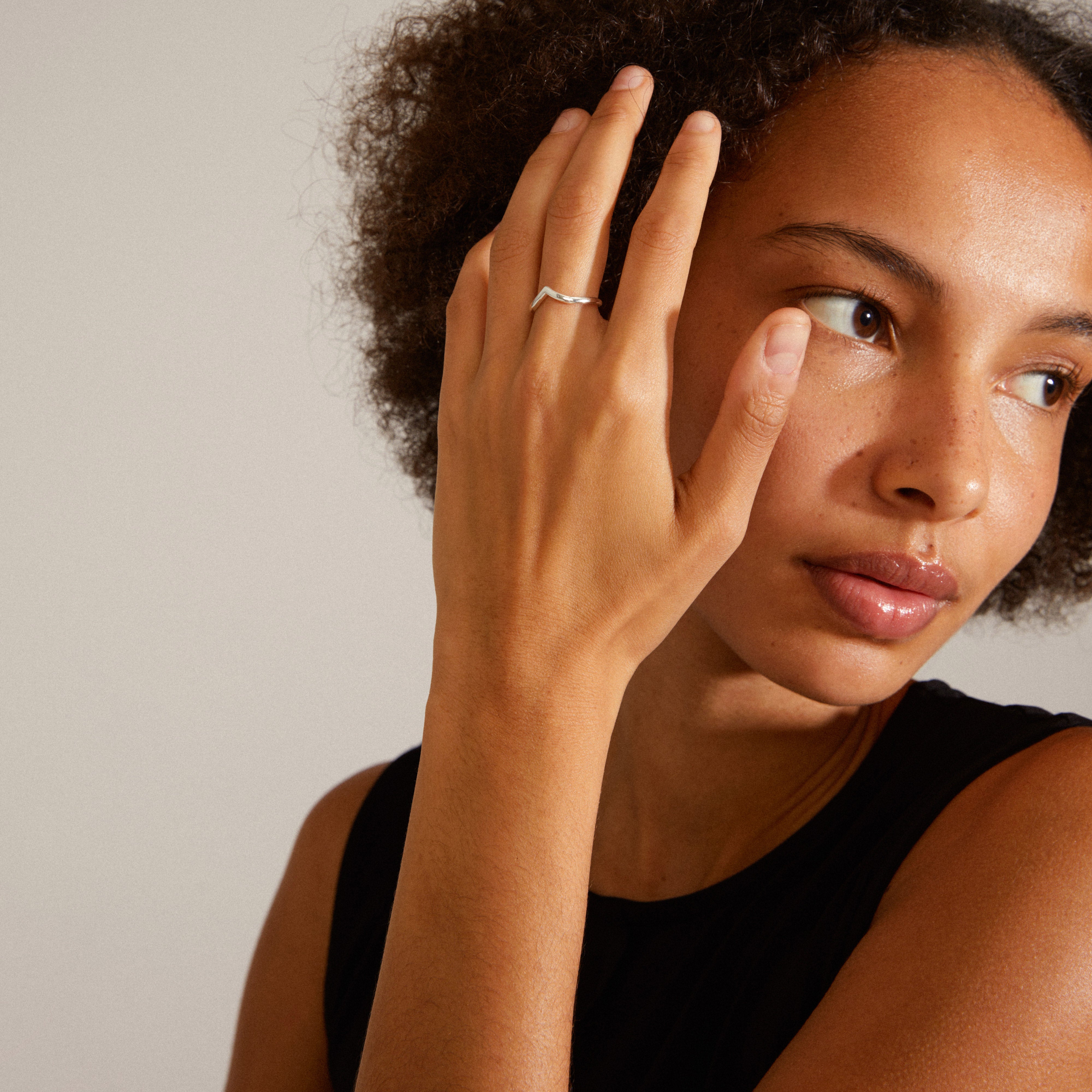 Woman with curly hair showcases the LULU stack ring, silver-plated, elegantly worn on her finger, highlighting its delicate and stylish design.