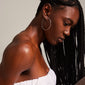 Woman with long braids wearing SANNE X-large silver-plated hoop earrings, showcasing the sleek, airy design and eye-catching size.