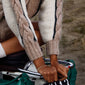 A person wearing a gold-plated PERI twirl bracelet, showcasing its chic, delicately twisted band, complemented by a green bag.