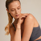 Woman wearing the gold-plated PAM robe chain bracelet, featuring a twisted cord design, hand elegantly placed on her shoulder. Classic style, trendy and timeless.