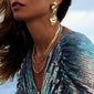 Woman wearing the gold-plated PAM robe chain necklace, featuring a chunky, twisted cord design, elegantly styled with gold earrings and a blue dress.