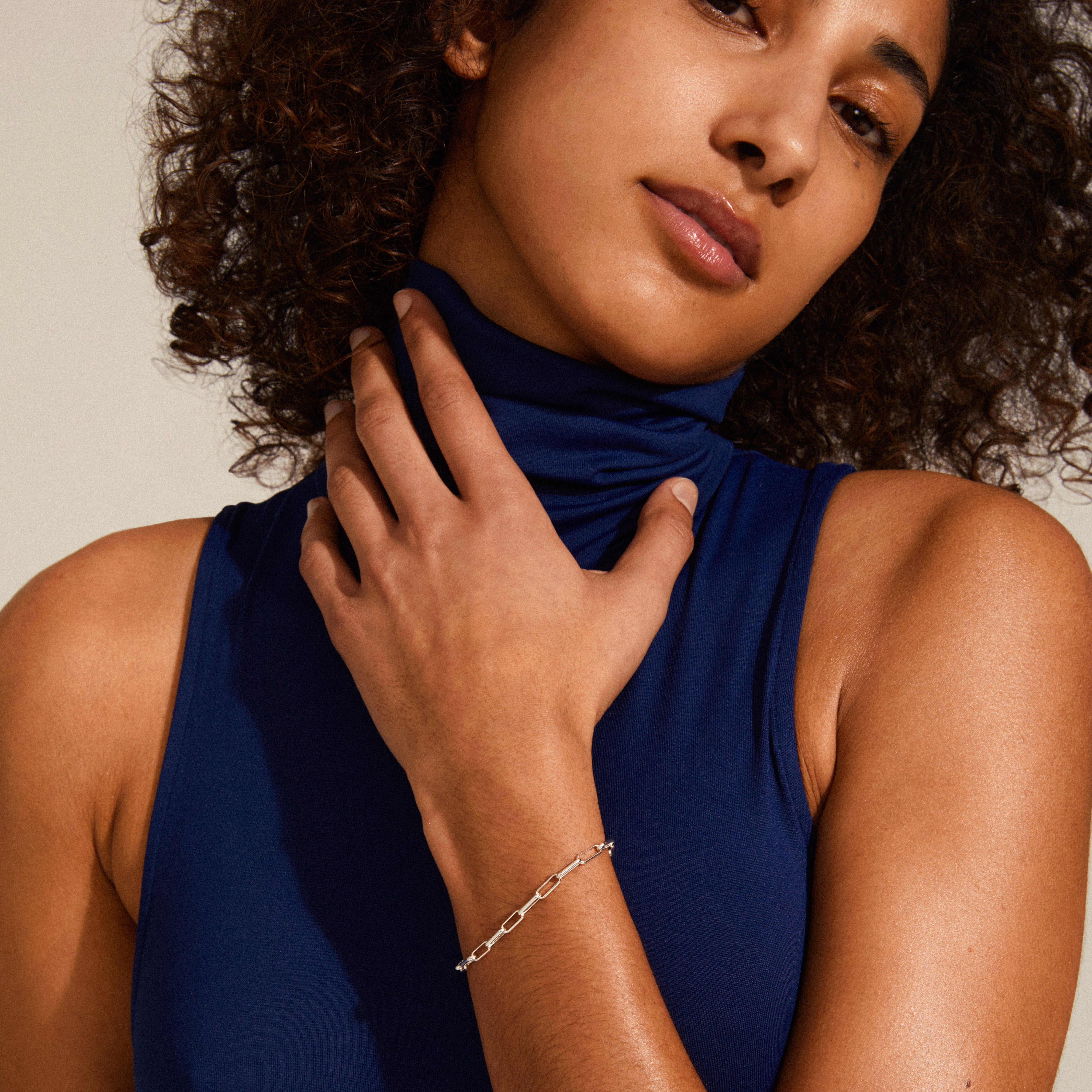 Silver-plated RONJA bracelet with rectangular links, worn by a woman with curly hair in a blue turtleneck, showcasing a bold, striking design.
