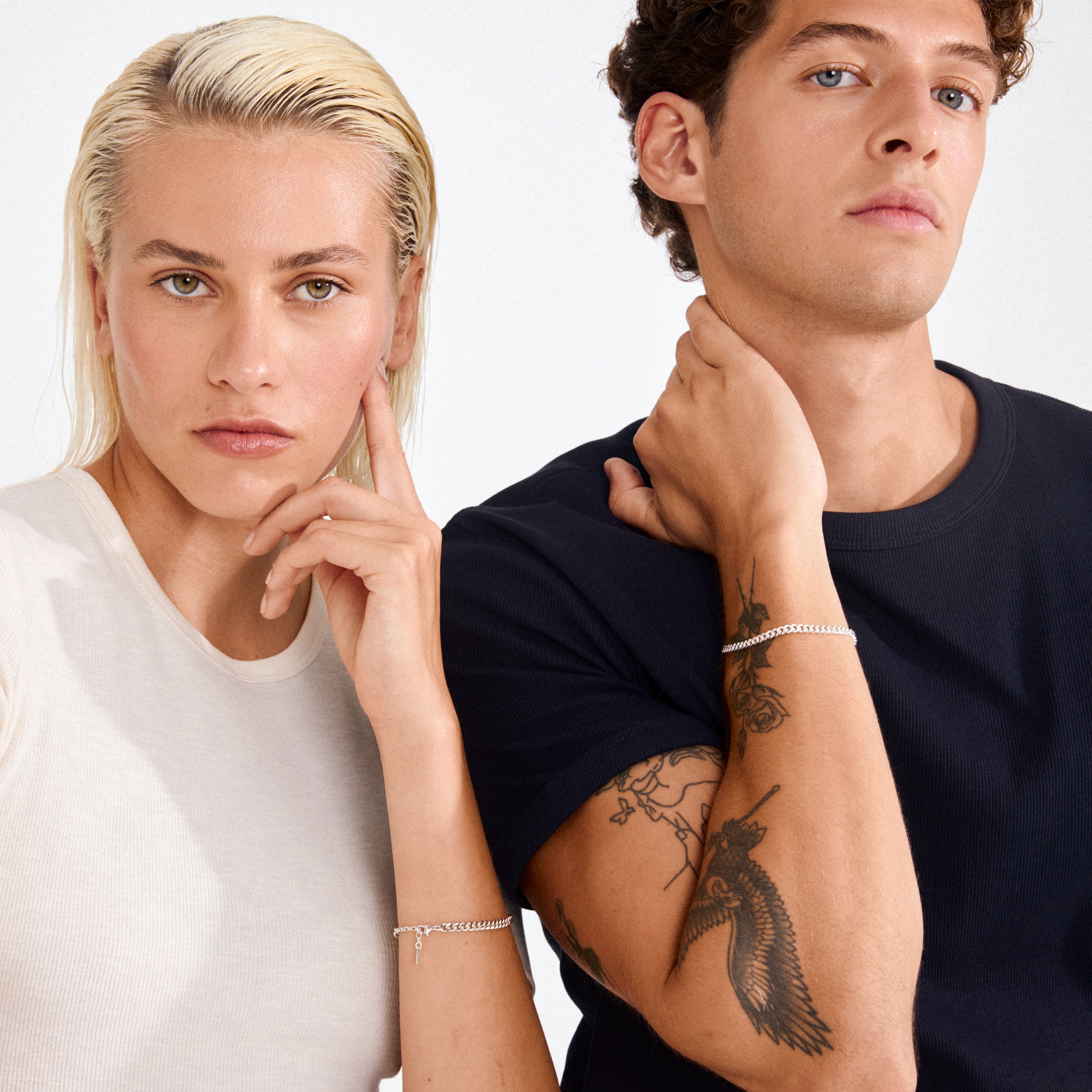 Two young adults showcase Pilgrim's FUCHSIA curb chain bracelet, silver-plated, on their wrists. The bracelet features a semi-chunky curb chain design.