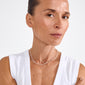 Woman wearing RONJA necklace silver-plated, featuring sleek rectangular links in a contemporary cable chain, accentuating a minimalist, stylish look against a light background.