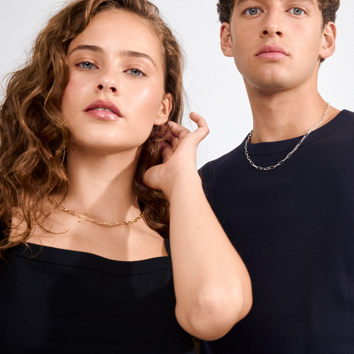 Close-up of models wearing the RONJA necklace: a silver-plated, sleek rectangular link chain, emphasizing minimalist style and crafted from recycled materials.