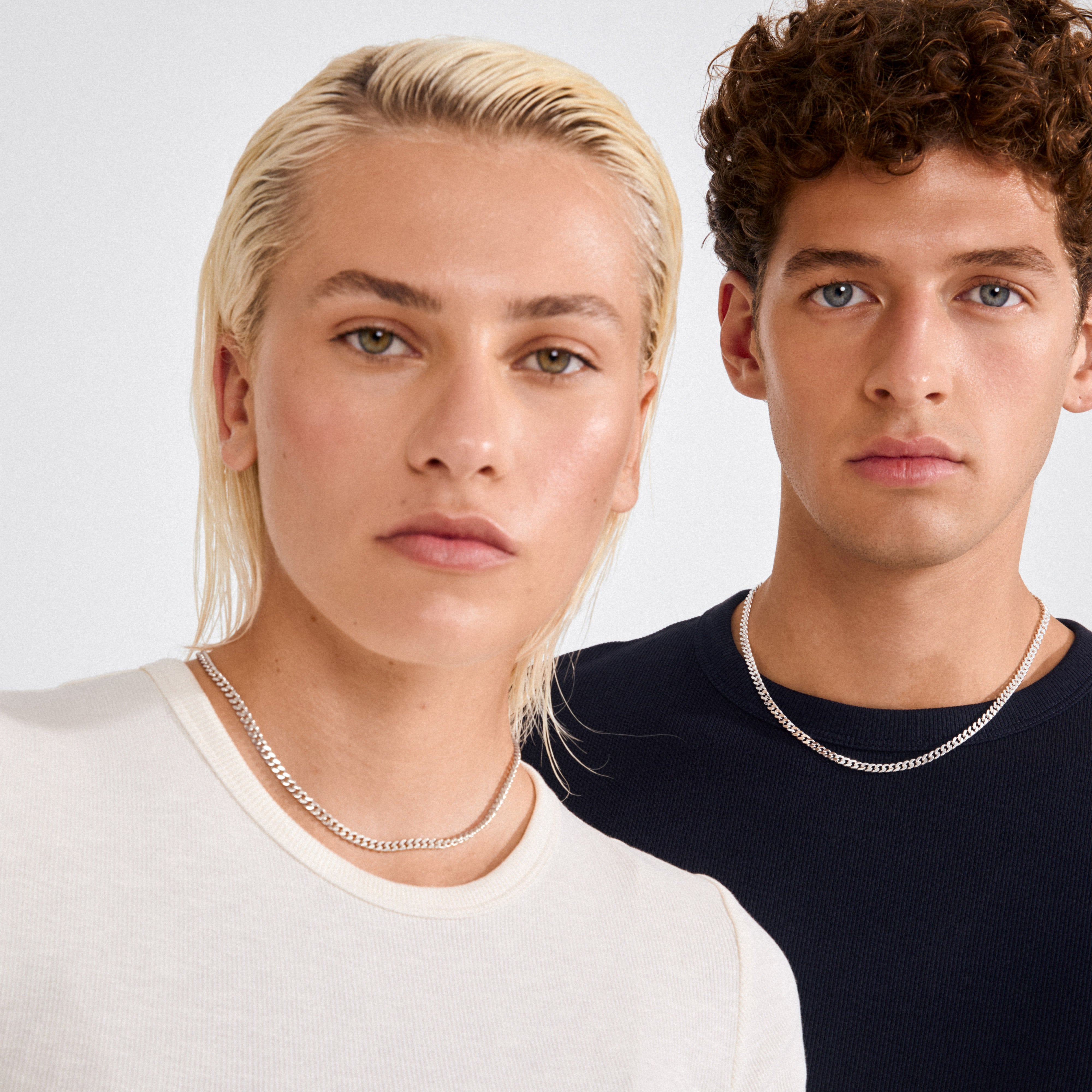 Two people wearing FUCHSIA curb chain necklaces, showcasing Pilgrim's silver-plated, semi-chunky style, highlighting timeless elegance and modern attitude.