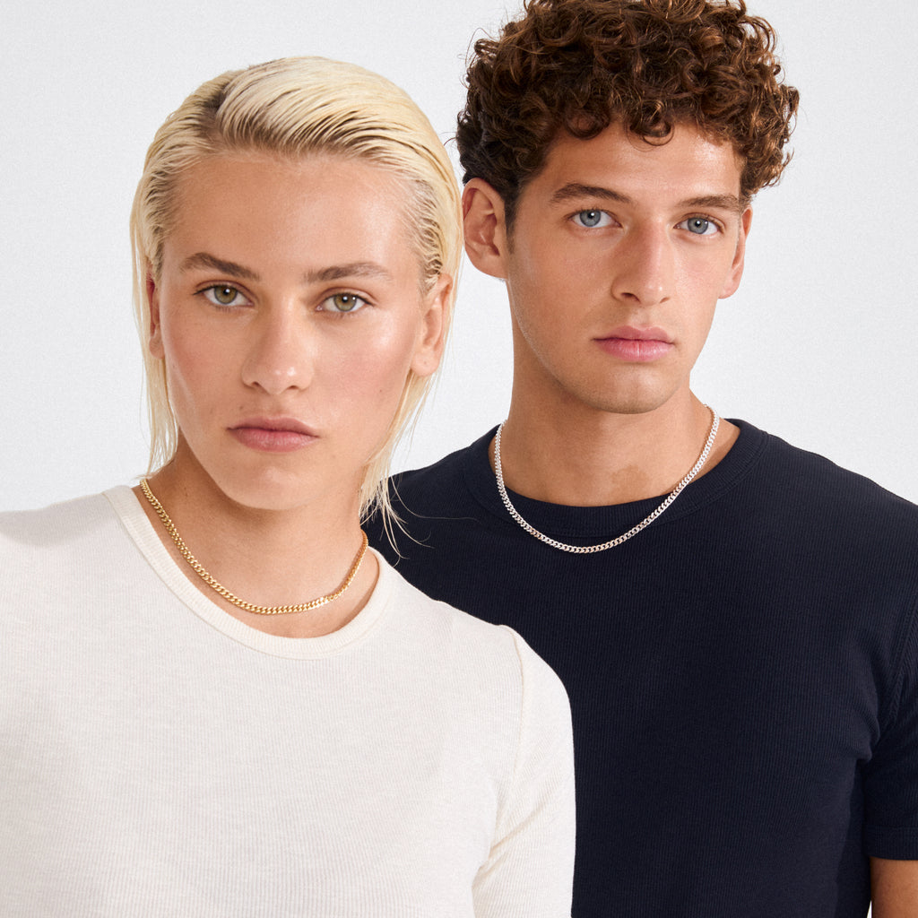 Two young adults wearing Pilgrim's FUCHSIA curb chain necklaces, silver-plated with faceted links, showcasing the semi-chunky, timeless style against a light background.