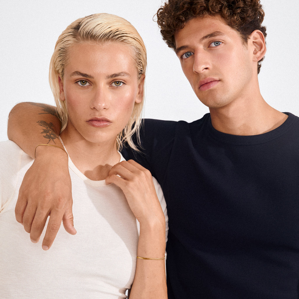 Two young adults showcase Pilgrim's JOANNA flat snake chain bracelet, highlighting its sleek, gold-plated design on her wrist, embodying effortless style and timeless appeal.