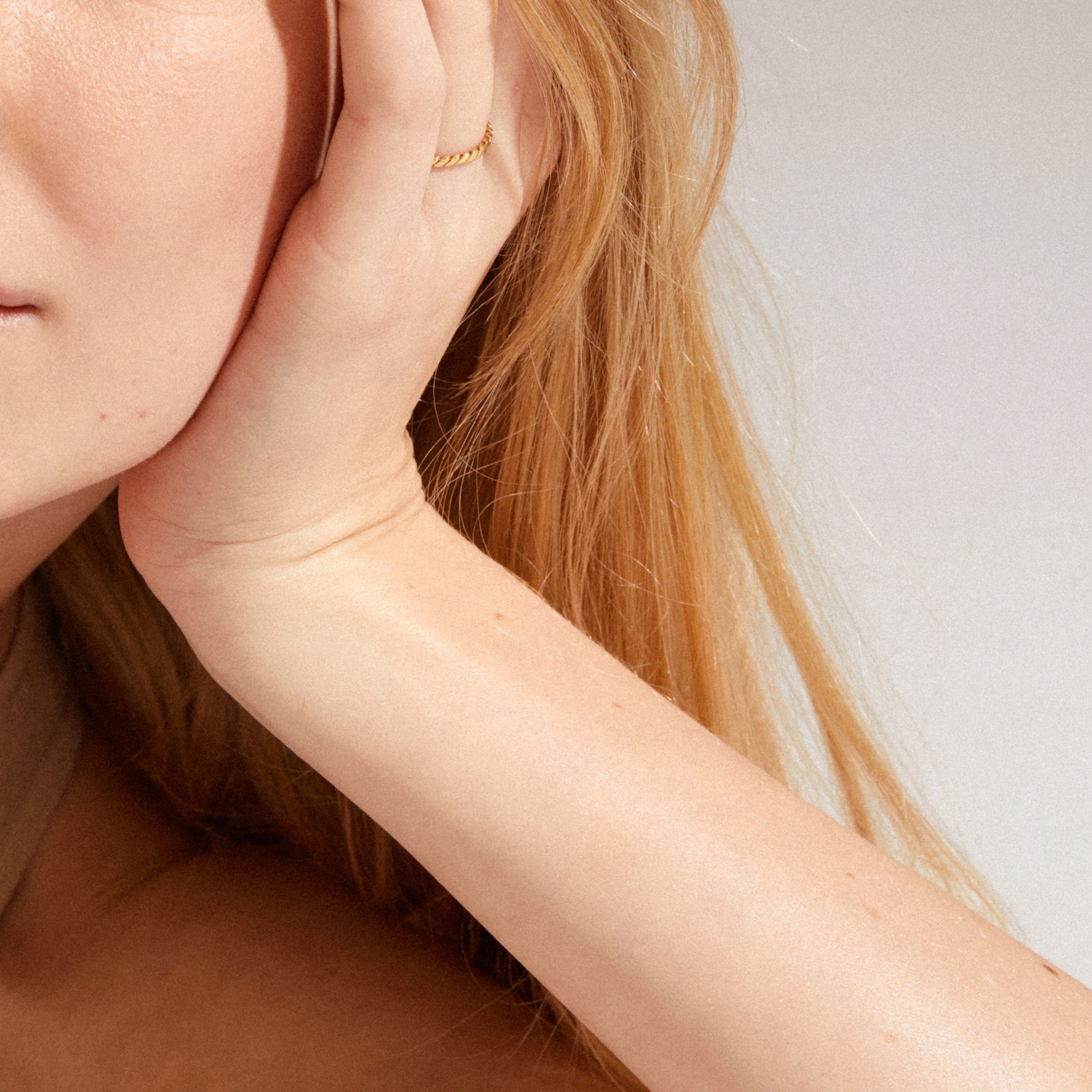 Close-up of a person's hand wearing the LULU twisted stack ring, gold-plated, showcasing its simple, stylish design inspired by cool chain trends.