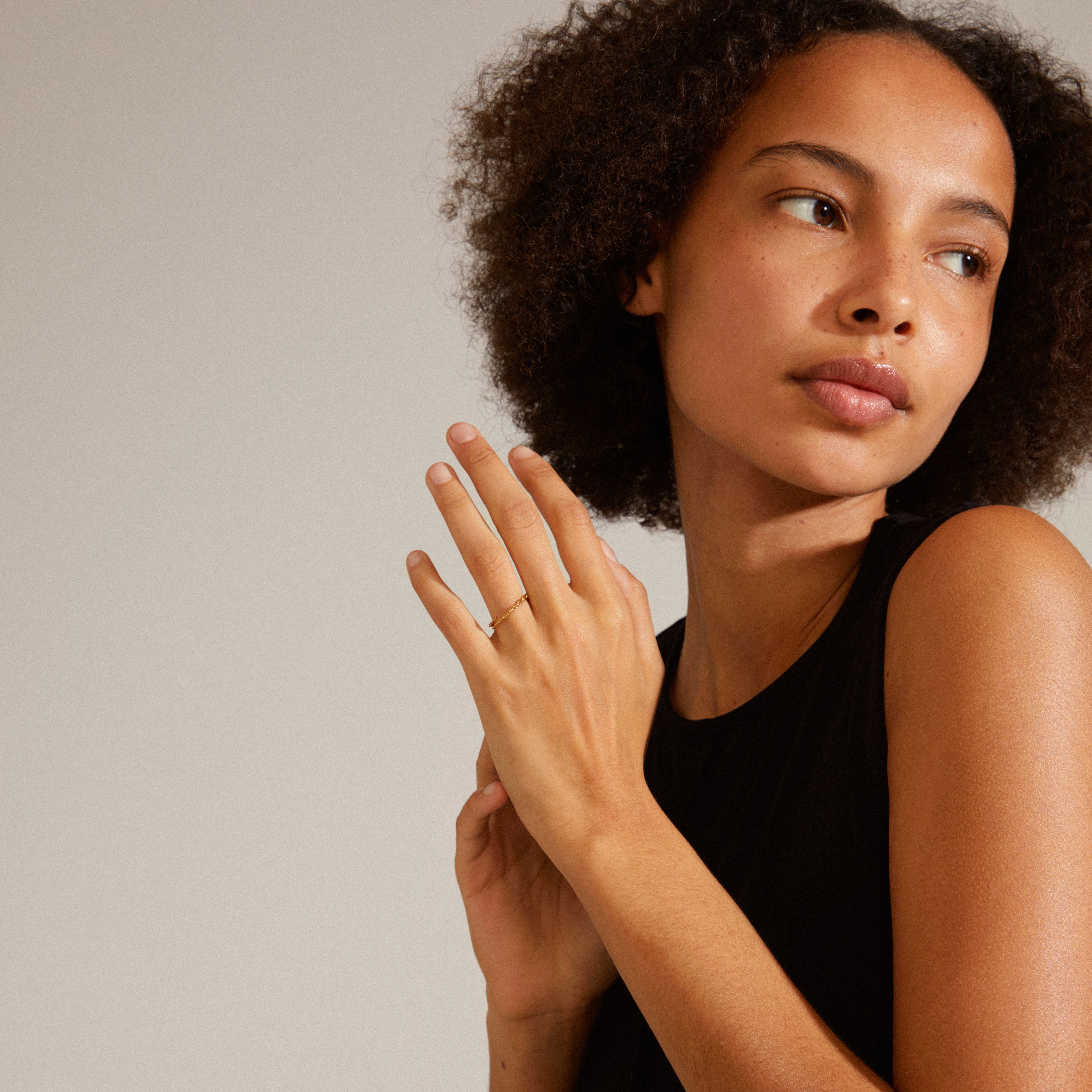 LULU chain stack ring gold-plated on a woman's finger, showcasing its elegant, chunky chain design; embodies Pilgrim's Scandinavian style and sustainability.