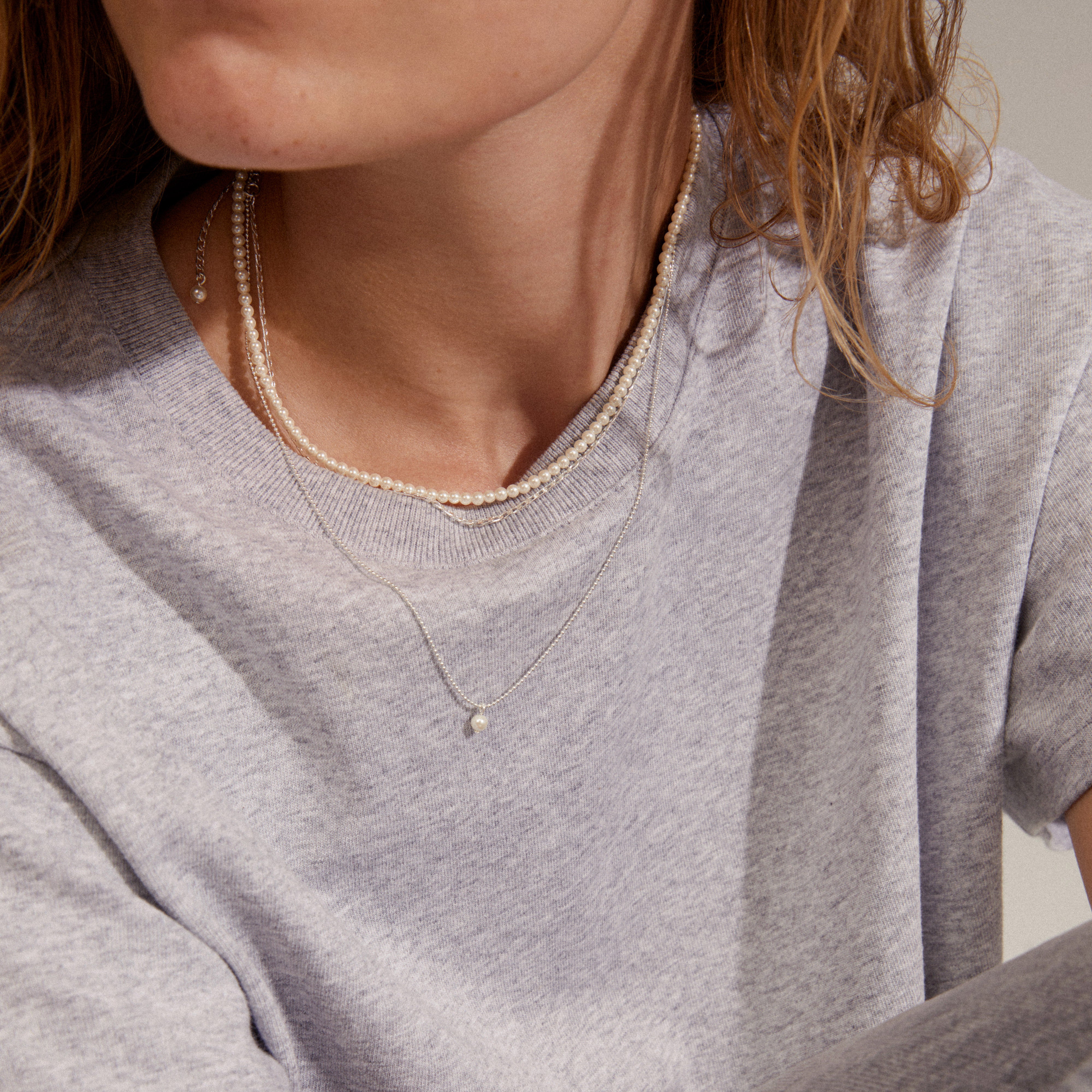 BAKER necklace 3-in-1 set silver-plated worn by a woman, showcasing three layered chains with pearls and trendy designs, perfect for versatile styling.