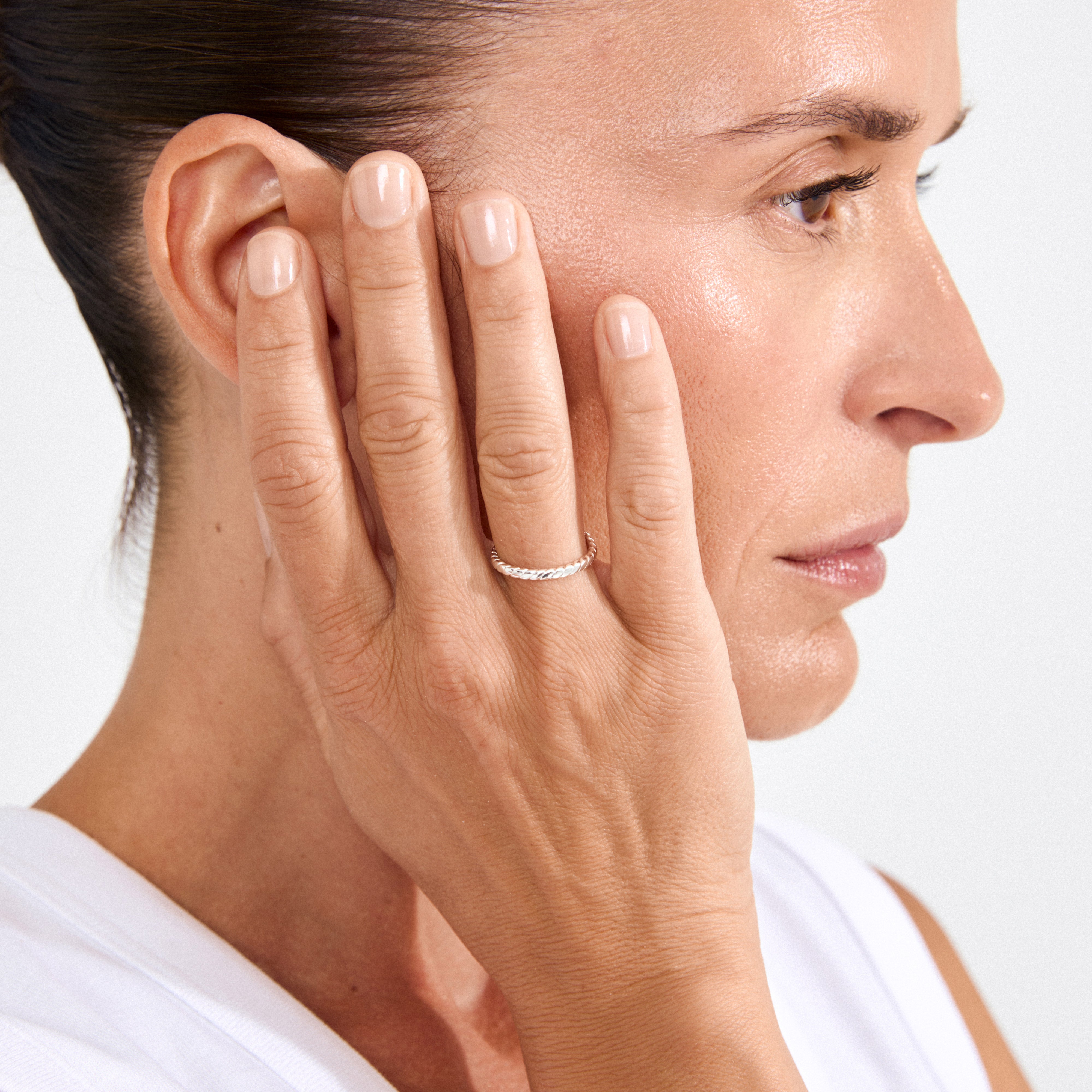 Woman's hand with manicured nails wearing the LULU twisted stack ring silver-plated, showcasing its elegant twisted-rope design against smooth, luminous skin.