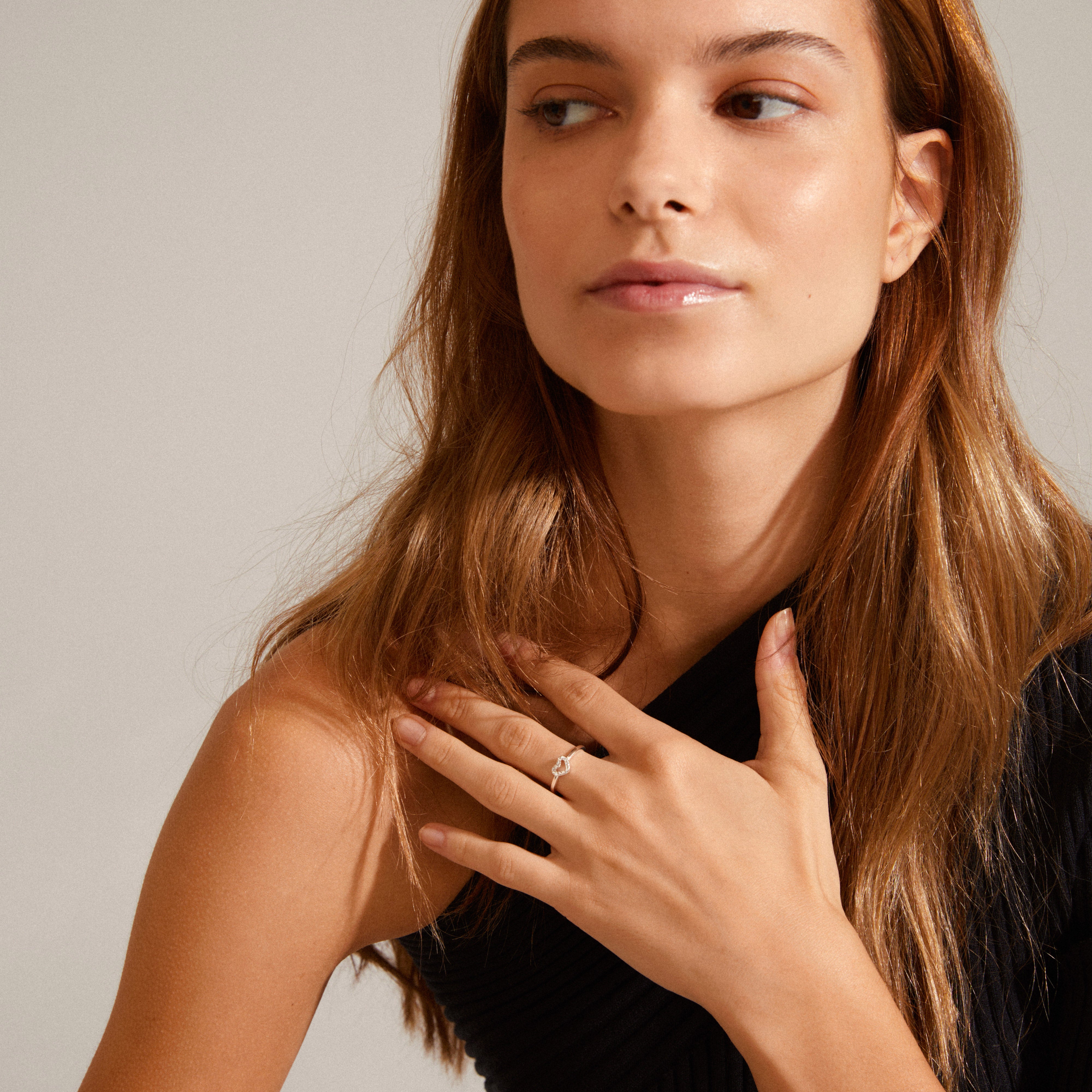 Woman wearing a black dress showcases the LULU crystal heart stack ring, silver-plated, adorned with Preciosa crystals, highlighting its elegant, stackable design.