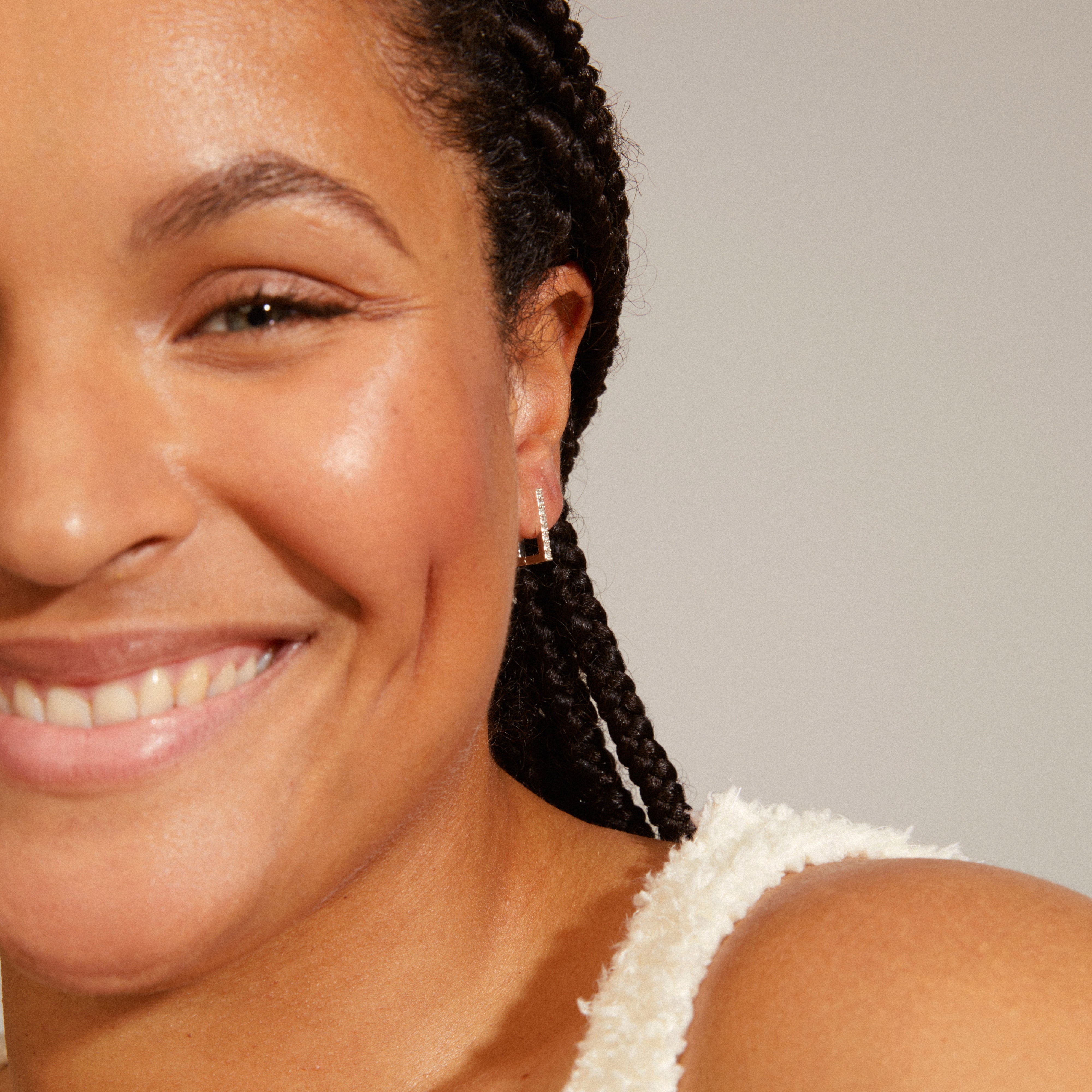 COBY crystal square hoop earrings, silver-plated, featuring Preciosa crystals, elegantly adorn a woman's ear, showcasing their angular and shiny design.
